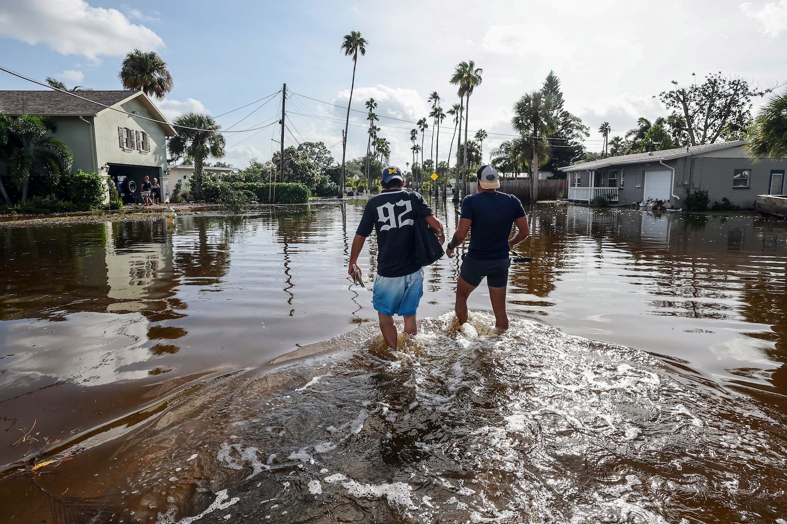 Thomas Chaves, left, and Vinny Almeida walk through floodwaters from Hurricane Helene in an attempt to reach Chaves's mother's house in the Shore Acres neighborhood Friday, Sept. 27, 2024, in St. Petersburg, Fla. (AP Photo/Mike Carlson)