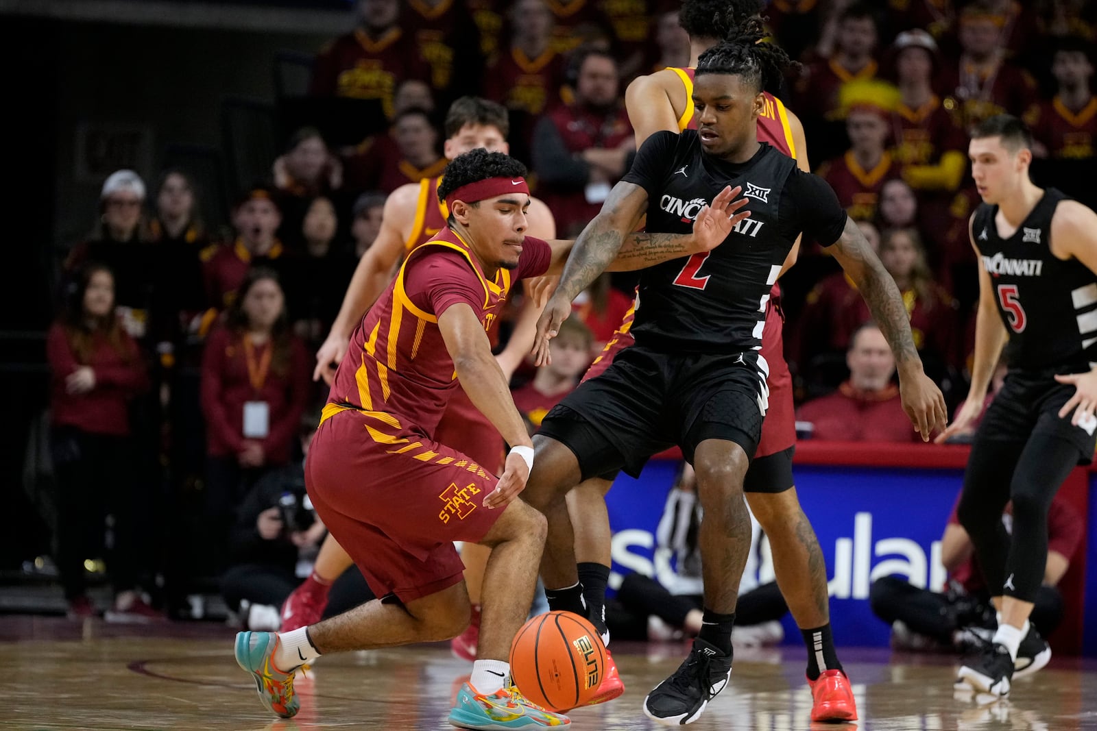 Cincinnati guard Jizzle James (2) tries to steal the ball from Iowa State guard Tamin Lipsey, left, during the first half of an NCAA college basketball game Saturday, Feb. 15, 2025, in Ames, Iowa. (AP Photo/Charlie Neibergall)