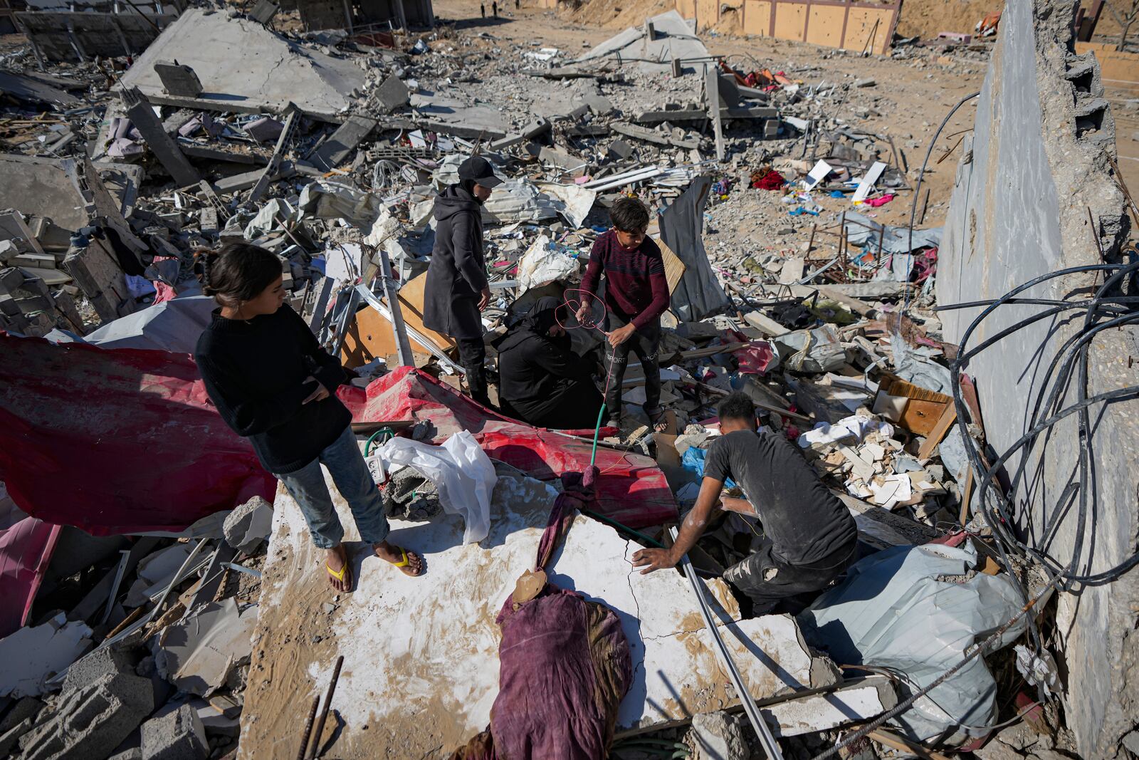 Members of the Abu Al Zamar family salvage items from under the rubble of their destroyed family home, in Rafah, southern Gaza Strip, Tuesday, Jan. 21, 2025, days after the ceasefire deal between Israel and Hamas came into effect. (AP Photo/Abdel Kareem Hana)