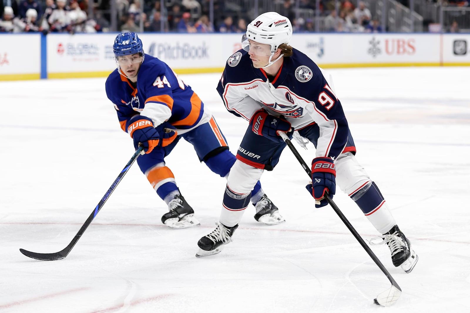 Columbus Blue Jackets center Kent Johnson (91) shoots and scores in front of New York Islanders center Jean-Gabriel Pageau, left, in the first period of an NHL hockey game Monday, Jan. 20, 2025, in Elmont, N.Y. (AP Photo/Adam Hunger)