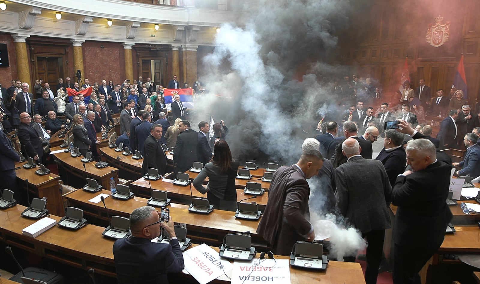 In this grab taken from video provided by RTS Serbia smoke bombs and flares are released in parliament, in Belgrade, Serbia, Tuesday, March 4, 2025. (RTS Serbia via AP)