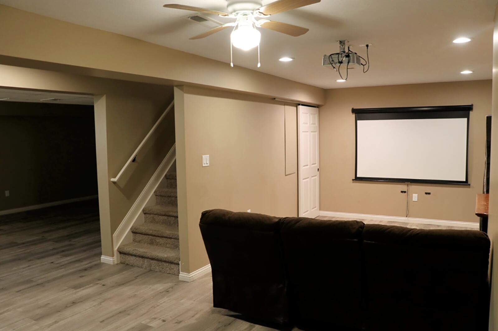 The stairwell divides the space into a spacious recreation room and a media room with projection system, screen and storage closet. A glass-panel door opens into a bonus room which could be an office or hobby area. CONTRIBUTED PHOTO BY KATHY TYLER