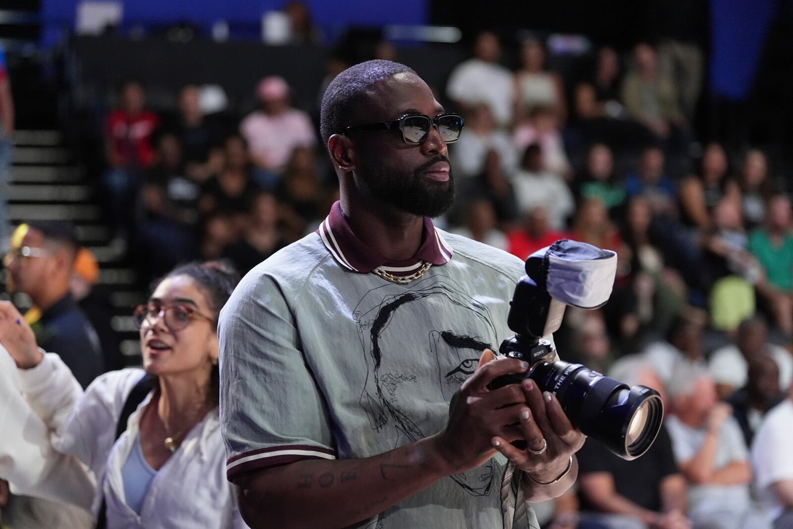 Former basketball player Dwayne Wade borrows a photographer's camera to take pictures, during halftime in the Unrivaled 3-on-3 basketball semifinal between the Lunar Owls and Vinyl, Sunday, March 16, 2025, in Medley, Fla. (AP Photo/Rebecca Blackwell)