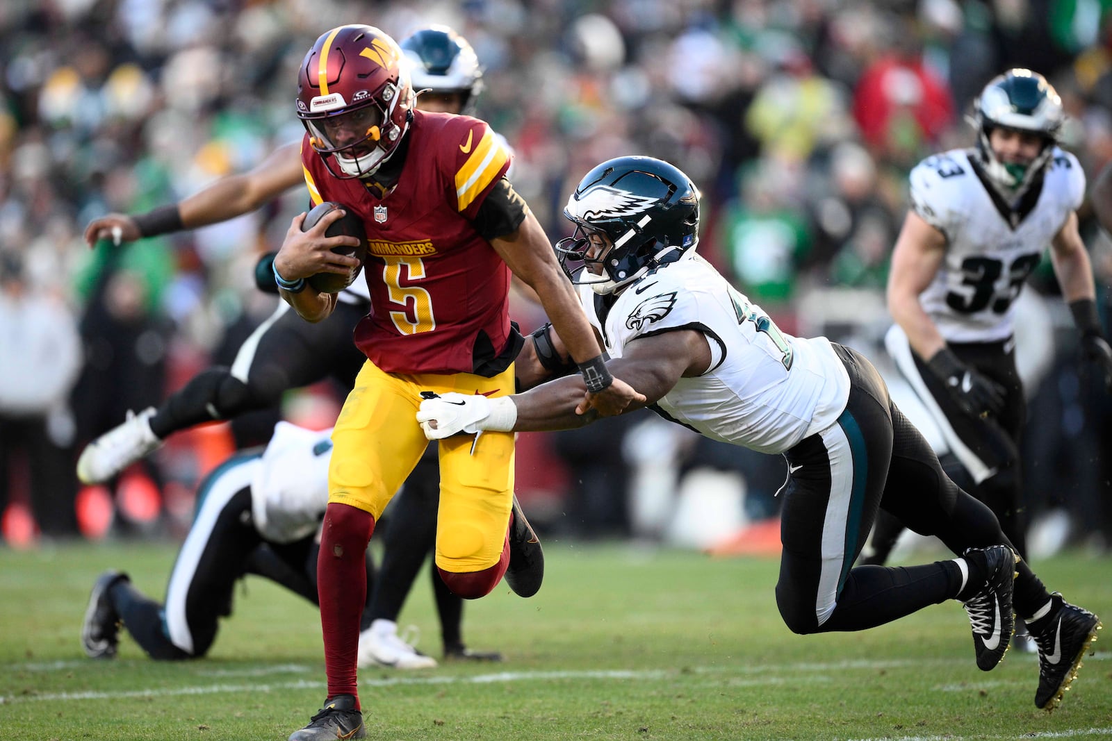 Washington Commanders quarterback Jayden Daniels (5) breaks away from Philadelphia Eagles linebacker Nakobe Dean (17) and runs with the ball during the second half of an NFL football game, Sunday, Dec. 22, 2024, in Landover, Md. (AP Photo/Nick Wass)