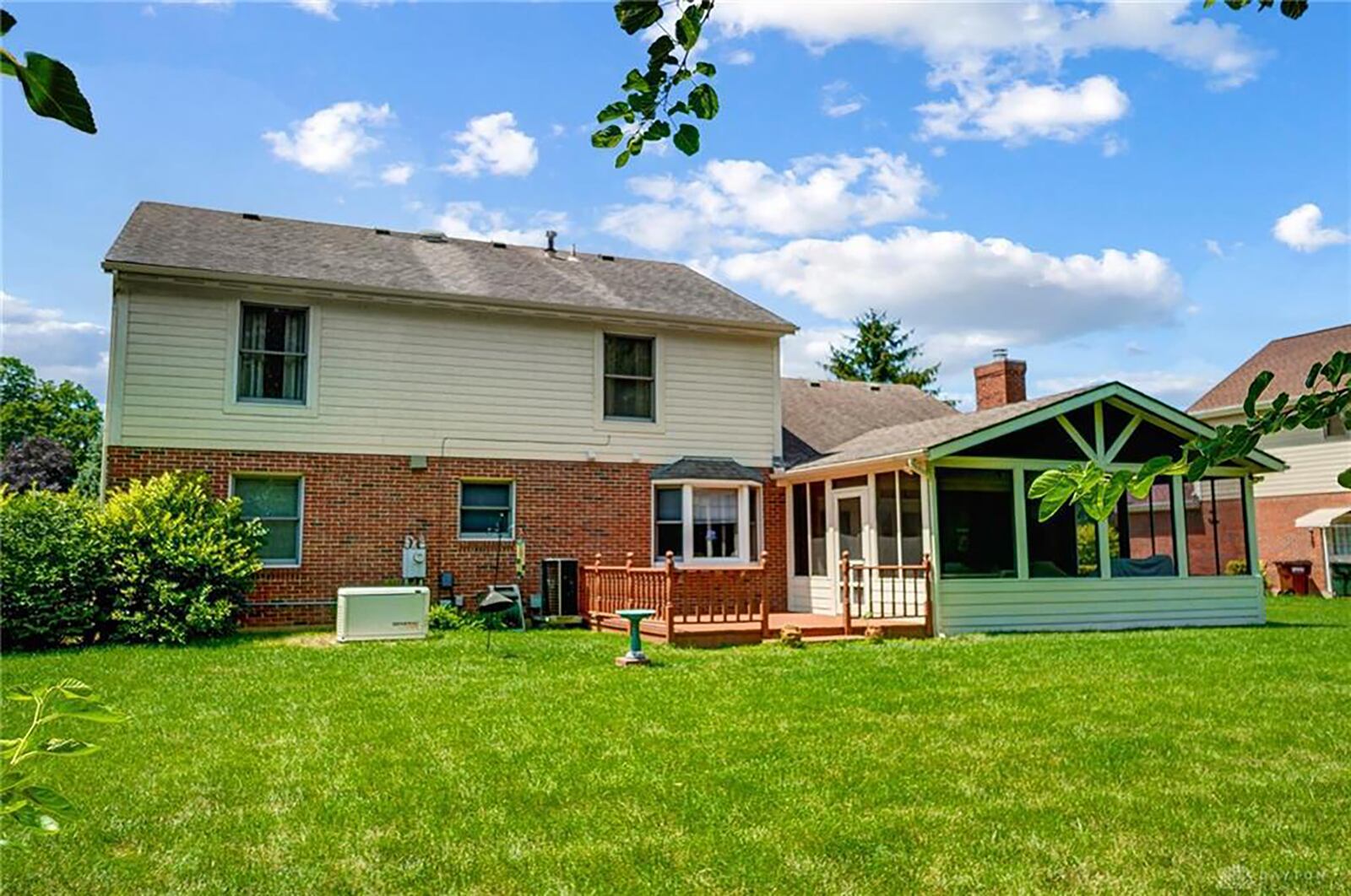 The rear of the home has a vaulted sunroom, wood deck with railing and an open back yard with privacy at the rear.