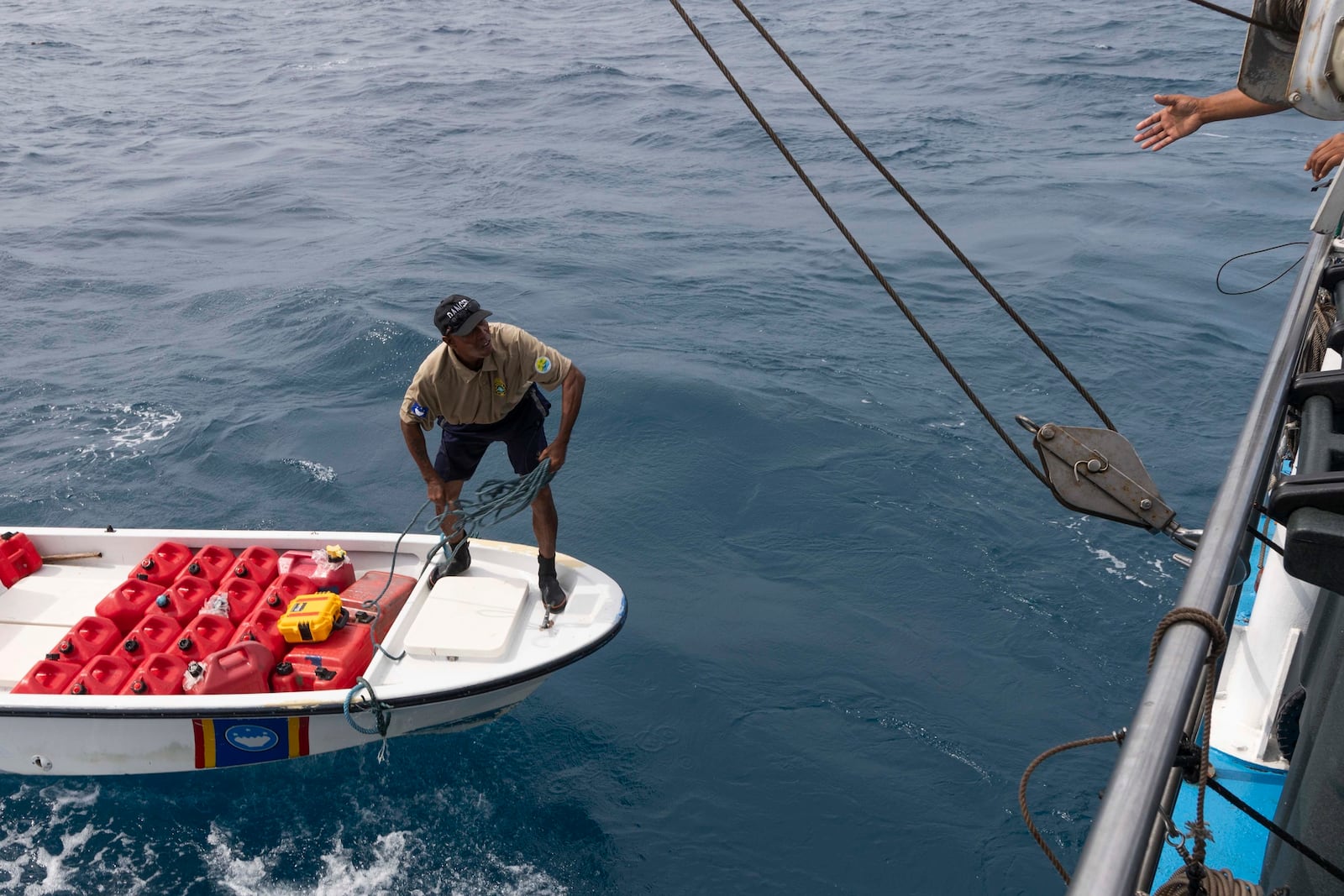 Fred Obak, a Hatohobei State Ranger stationed on Helen Island, Palau, throws a rope to a boat as they prepare to exchange fuel cans on July 17, 2024. (AP Photo/Yannick Peterhans)