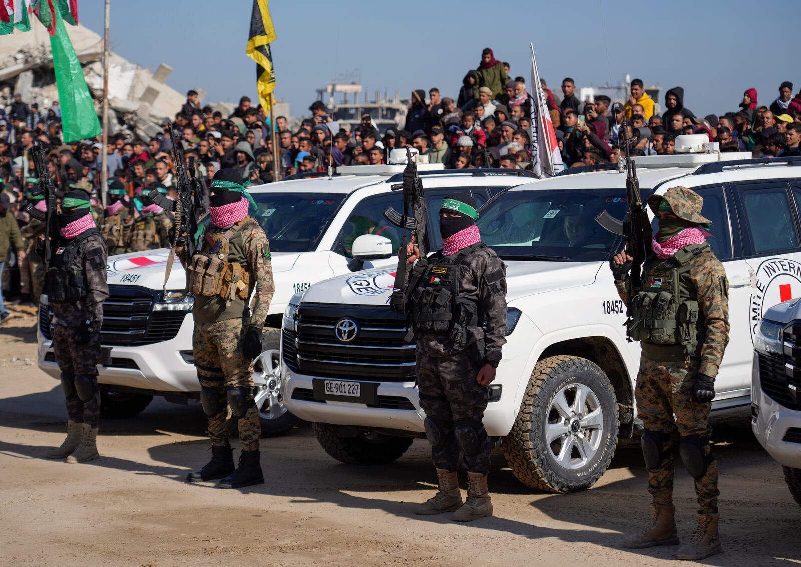 Hamas fighters takes up a position in front of International red cross cars wait for Israeli captives, Iair Horn, Alexander (Sasha) Troufanov and Sagui Dekel Chen, who has been held hostage in Gaza since October 7, 2023, in Khan Younis, southern Gaza Strip, Saturday Feb. 15, 2025. (AP Photo/Abdel Kareem Hana)