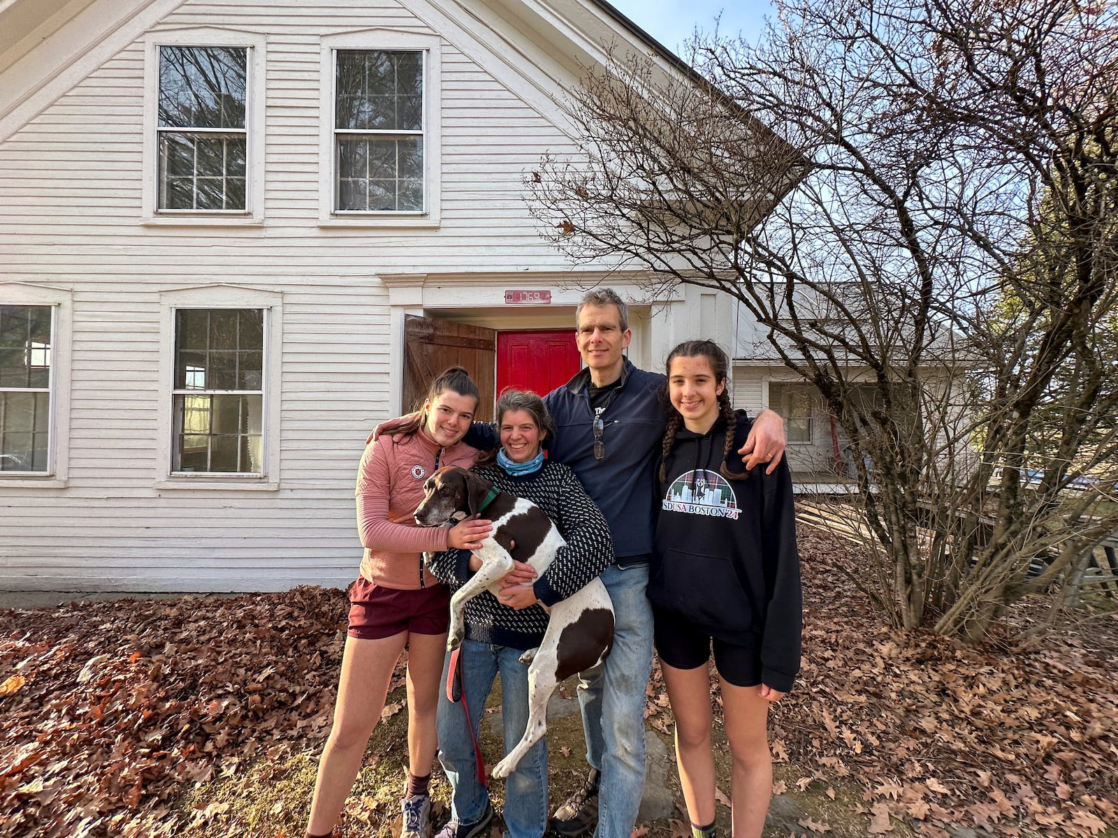 The Mackenzies, from left to right, Lila, Jenny, John, Kate and their dog Hester pose in front of their new house in Craftsbury, Vt. on Nov. 17, 2024. (AP Photo/Lisa Rathke)