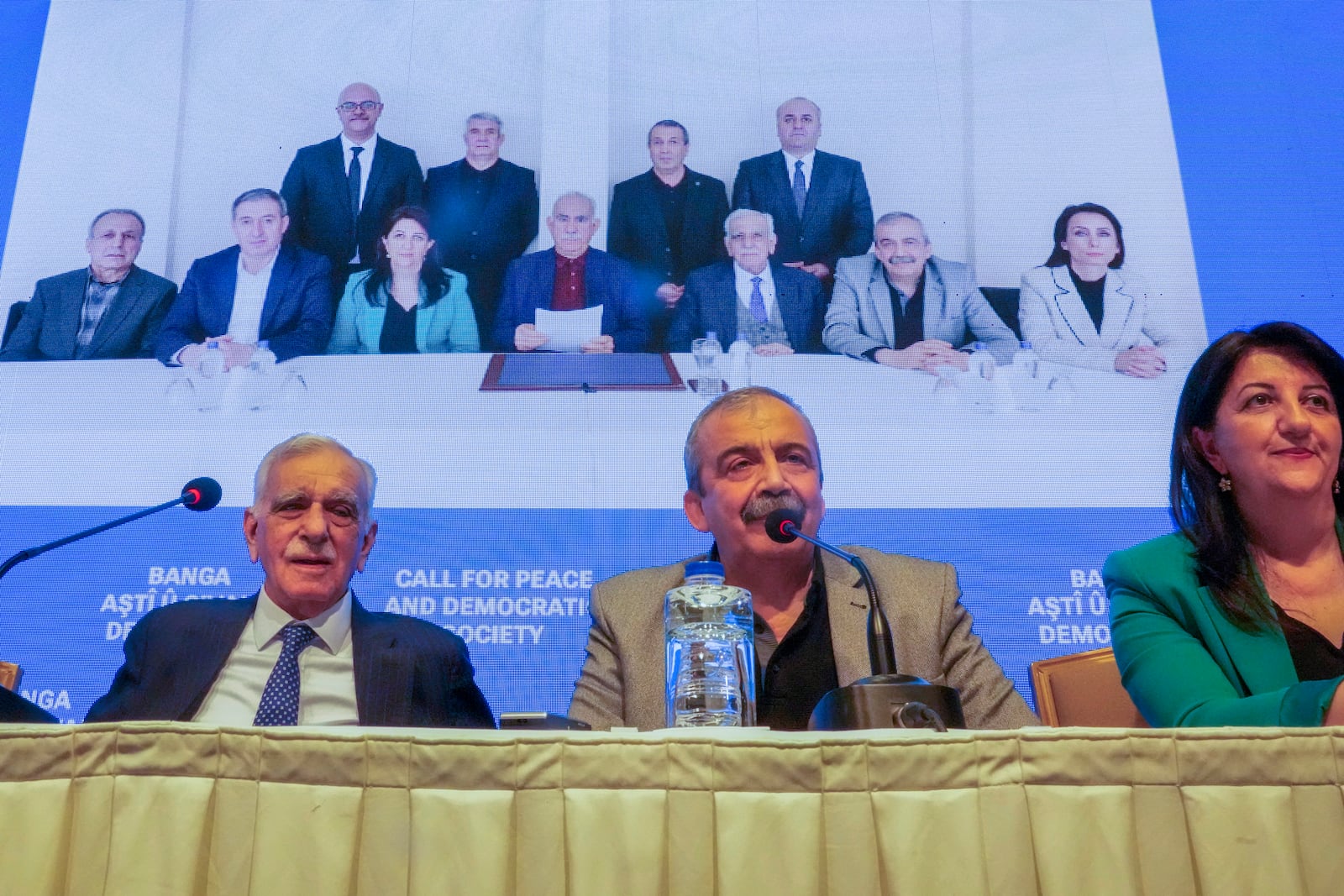 Pro-Kurdish Peoples' Equality and Democracy Party, or DEM, delegation members release an statement from the jailed leader of the rebel Kurdistan Workers' Party, or PKK, Abdullah Ocalan, center at the background photo, in Istanbul, Turkey, Thursday, Feb. 27, 2025. (AP Photo/Khalil Hamra)