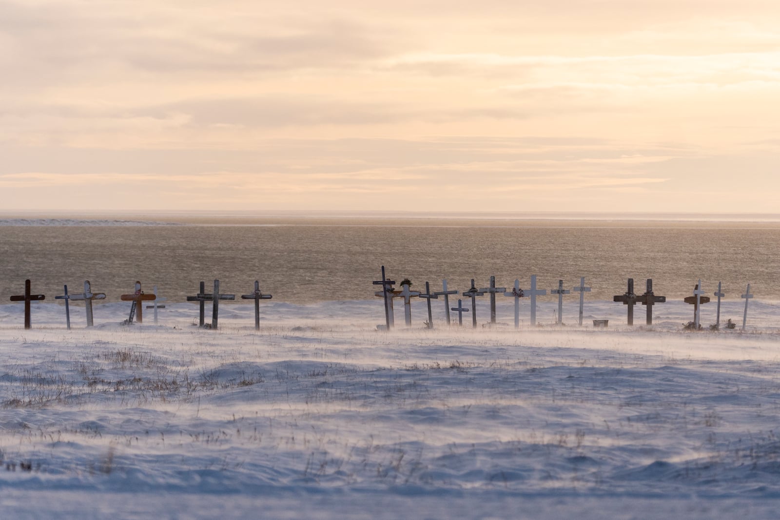 Wind blows snow along the surface of the village cemetery looking towards the Kaktovik Lagoon and the coastal plain of the Arctic National Wildlife Refuge, in Kaktovik, Alaska, Monday, Oct. 14, 2024. (AP Photo/Lindsey Wasson)