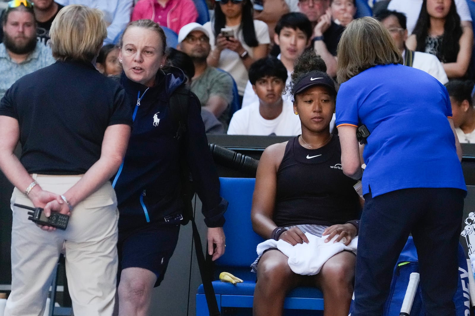 Naomi Osaka of Japan receives treatment from a trainer during her third round match against Belinda Bencic of Switzerland at the Australian Open tennis championship in Melbourne, Australia, Friday, Jan. 17, 2025. (AP Photo/Manish Swarup)