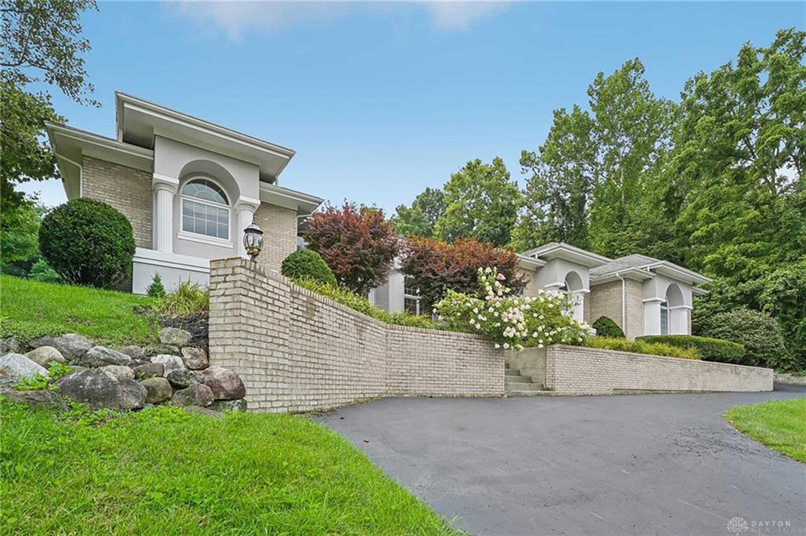 the front of the home has a brick retaining wall separating the front from the driveway. Concrete steps lead to the front entry.