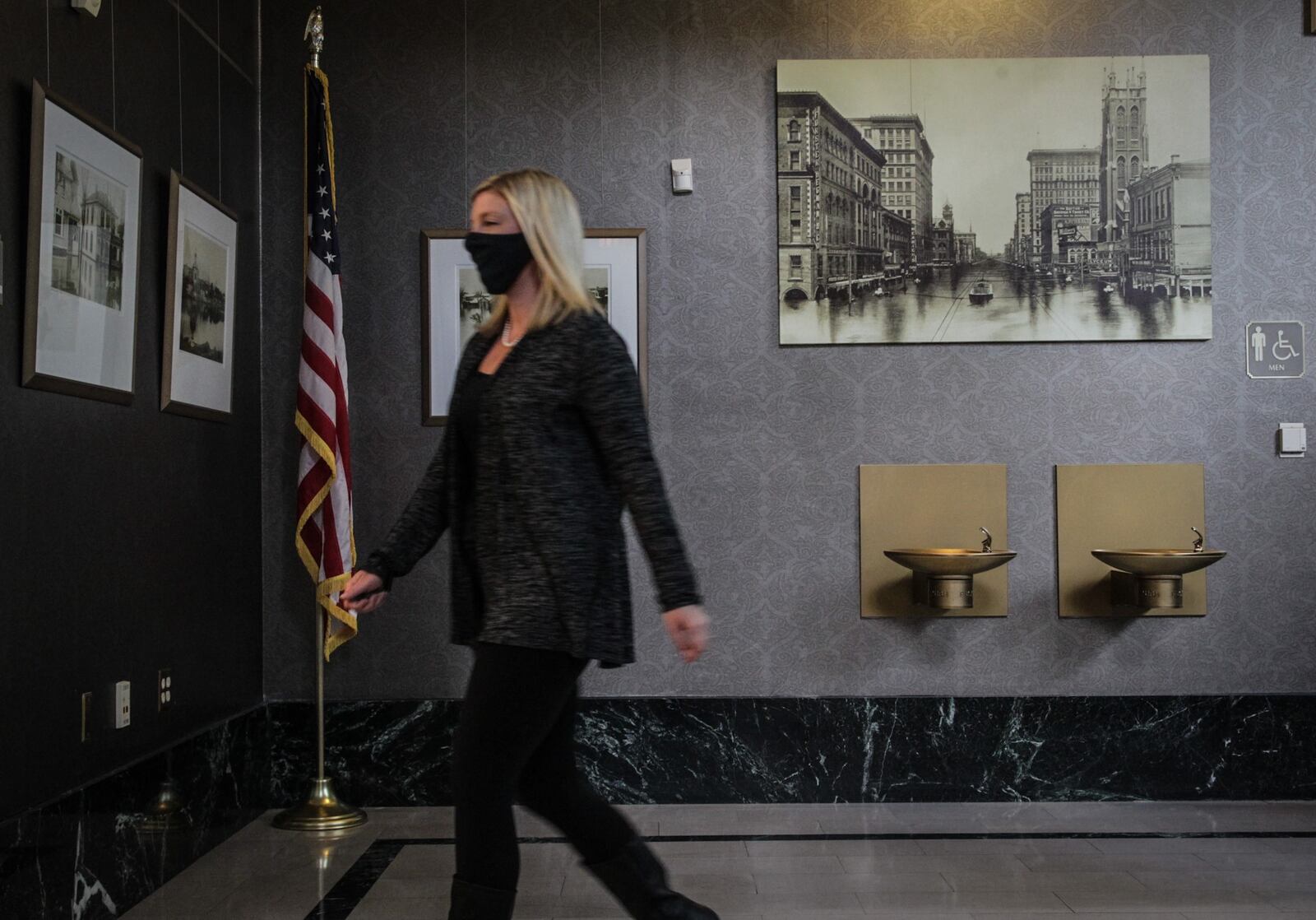 Shannon Phelps, manager of administration at the Miami Conservancy District, walks by photos from the Great Flood at the district's downtown Dayton headquarters. The district adapted a hybrid workplace during the COVID-19 pandemic, with employees taking turns coming into the office.