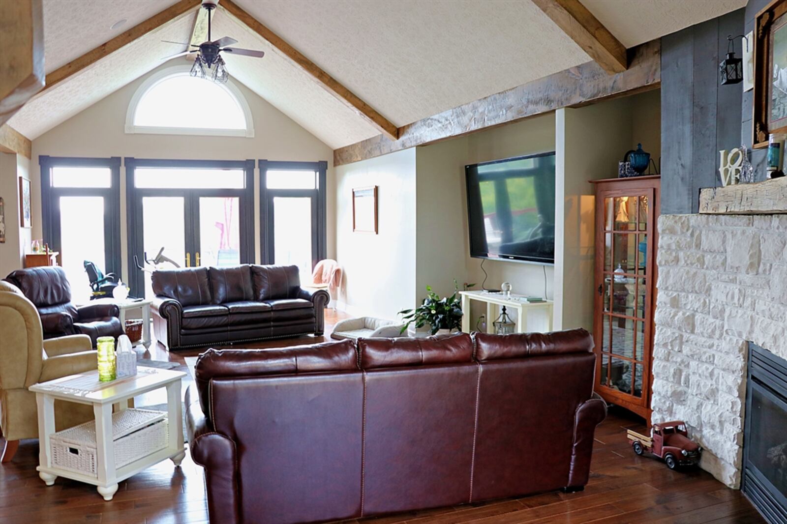 White stone curves within a nook of the great room to surround the gas fireplace, which has a barn-beam mantel.