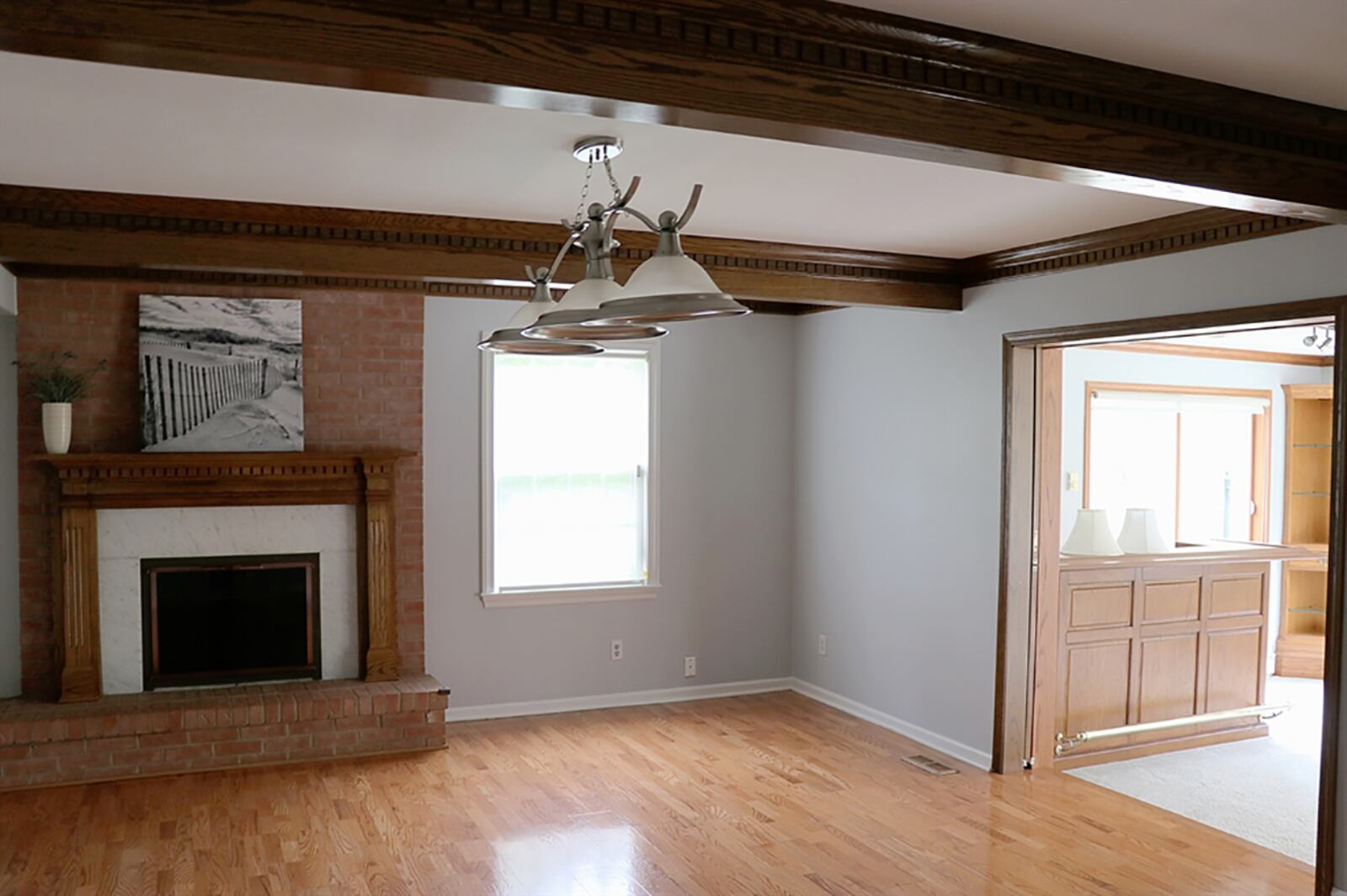 Dentil wood beams accent the ceiling of the family room and complement the wood mantel and woodwork surrounding the brick fireplace. The fireplace is tucked off to one side and has a raised brick hearth and is flanked by one large side-facing window. CONTRIBUTED PHOTO BY KATHY TYLER