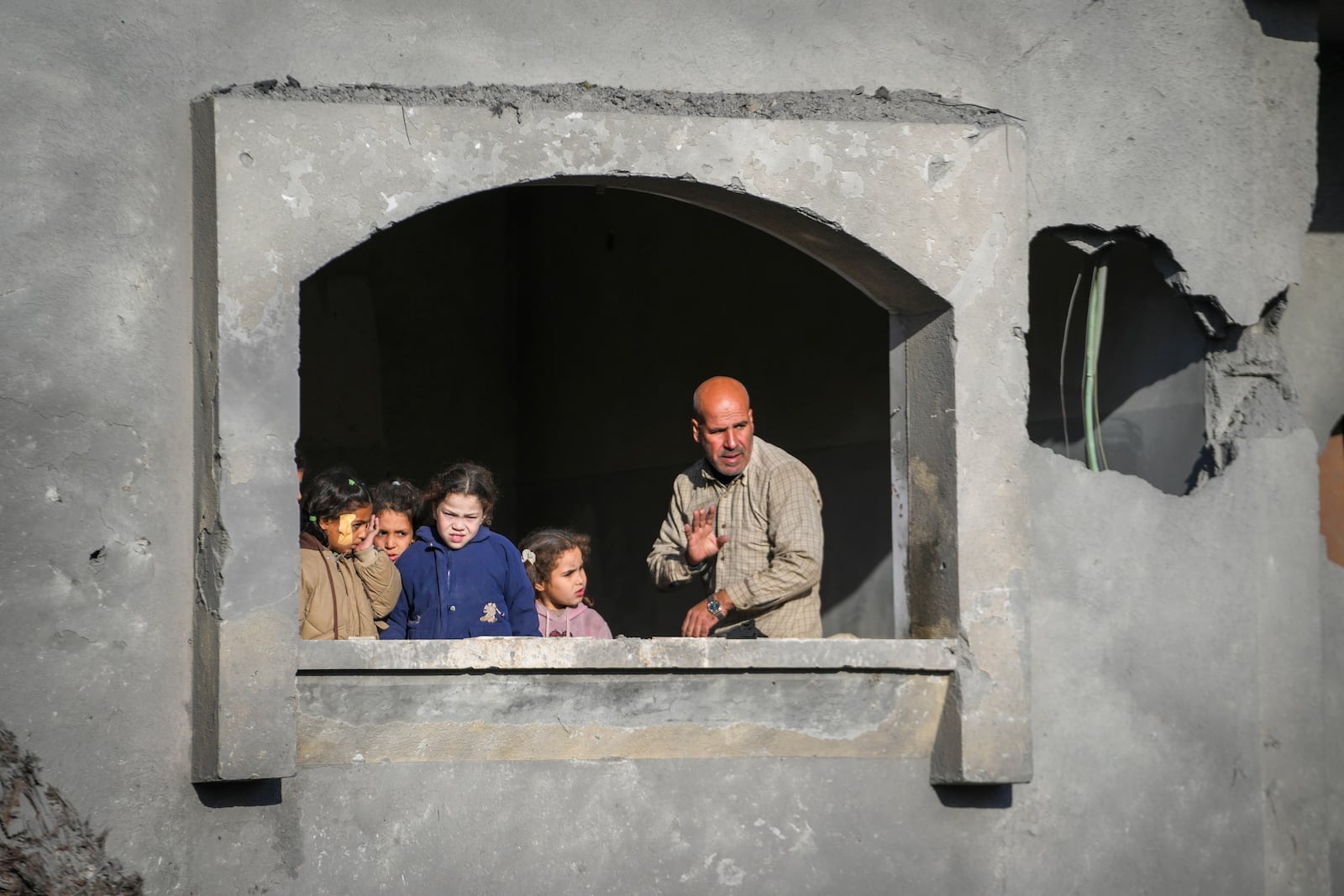 Neighbours watch the funeral procession of the victims of an Israeli strike on a home late Saturday, in Deir al-Balah, central Gaza Strip, Sunday, Dec. 22, 2024. At least eight people were killed according to the hospital which received the bodies.(AP Photo/Abdel Kareem Hana)