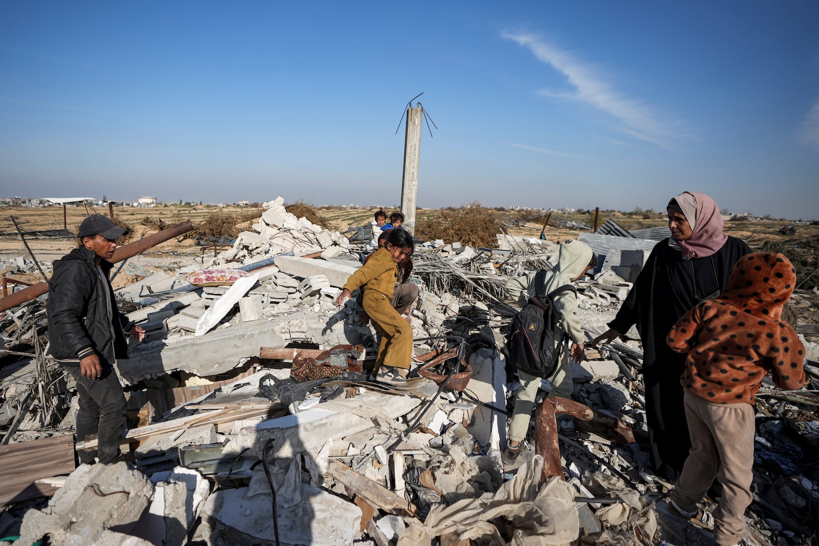 Members of the Abu Sheiban family salvage what they can of their belongings from under rubble of their destroyed home, days after the ceasefire deal between Israel and Hamas, in Rafah, southern Gaza Strip, Tuesday, Jan. 21, 2025. (AP Photo/Abdel Kareem Hana)