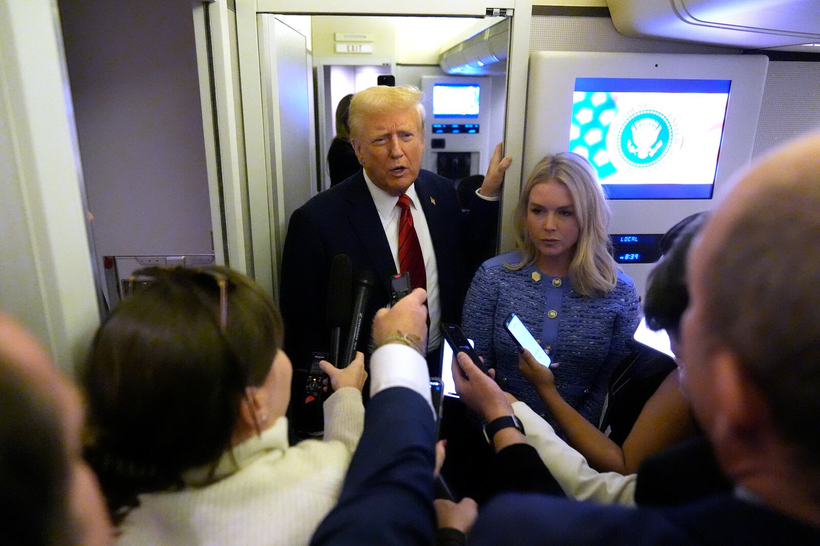 FILE - President Donald Trump speaks to reporters aboard Air Force One en route from Miami to Joint Base Andrews, Md., Jan. 27, 2025, as White House press secretary Karoline Leavitt listens. (AP Photo/Mark Schiefelbein, File)