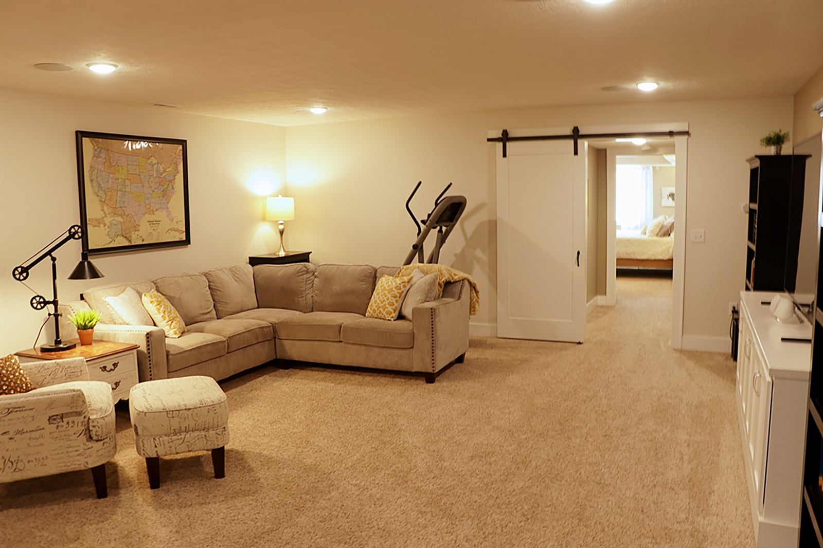 Downstairs, the stairwell ends directly into a family room with a built-in media cabinet and carpeting. Double sliding barn doors open into a multipurpose room with a kitchenette with shiplap accents and media connections between hanging cabinets. CONTRIBUTED PHOTO BY KATHY TYLER