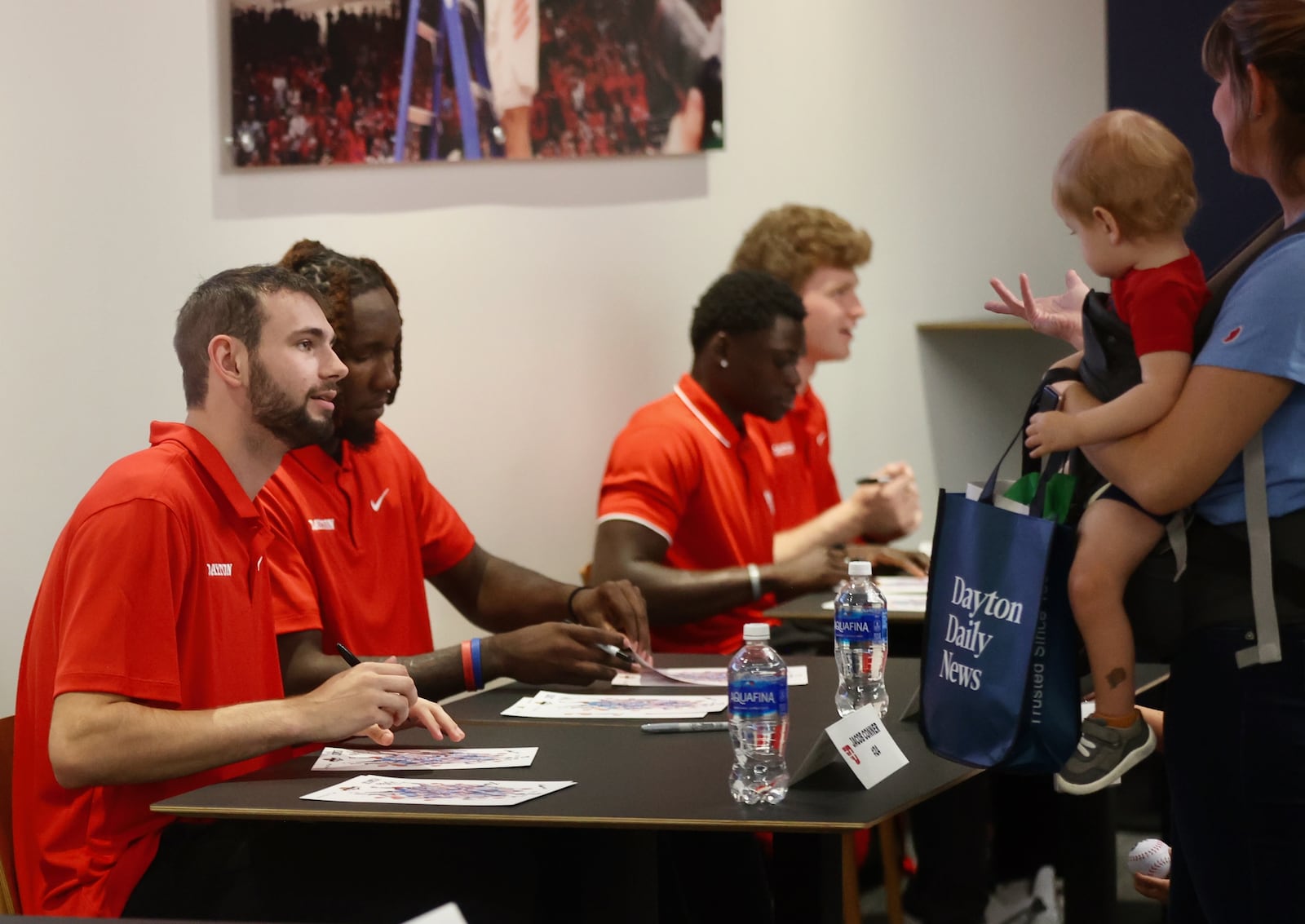 Dayton players, including Jacob Conner, left, sign autographs during a meet and greet with fans on Wednesday, Oct. 9, 2024, at UD Arena. David Jablonski/Staff