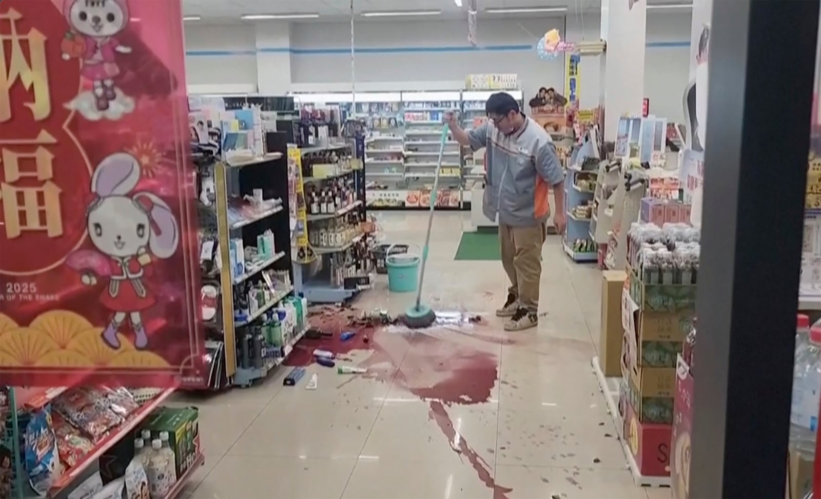 In this image from a video, a store worker cleans the floor in Tainan, Taiwan Tuesday, Jan. 21, 2025 after an earthquake. (TVBS via AP)