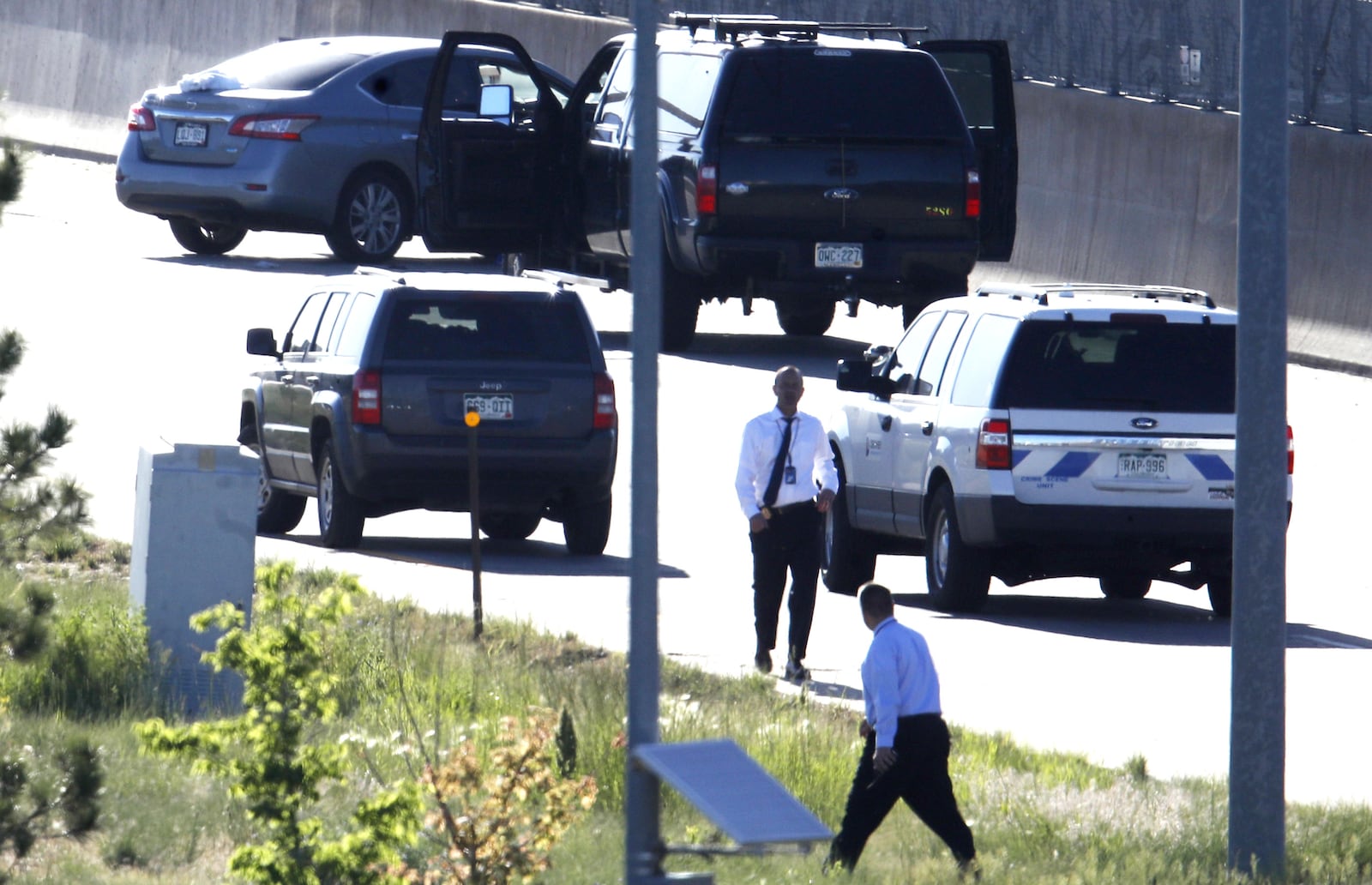 Denver Police Department detectives, foreground, investigate the scene where a Nissan sedan, top left, driven by Uber driver Michael Hancock crashed into a retaining wall along Interstate 25 near downtown Denver early Friday, June 1, 2018. Hancock, 29, is accused of shooting and killing a passenger at 2:45 a.m. after a confrontation broke out between the two men while headed southbound on the interstate.