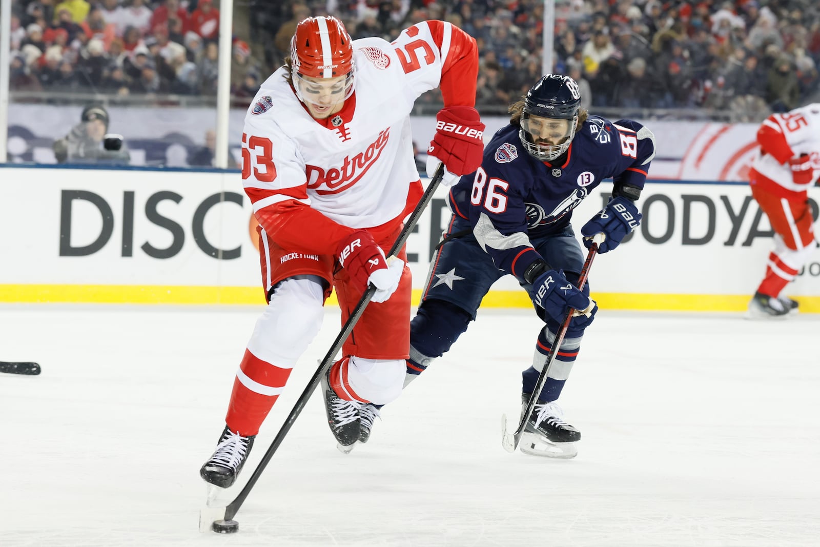 Detroit Red Wings' Moritz Seider, left, tries to clear the puck as Columbus Blue Jackets' Kirill Marchenko defends during the second period of the Stadium Series NHL hockey game at Ohio Stadium Saturday, March 1, 2025, in Columbus, Ohio. (AP Photo/Jay LaPrete)