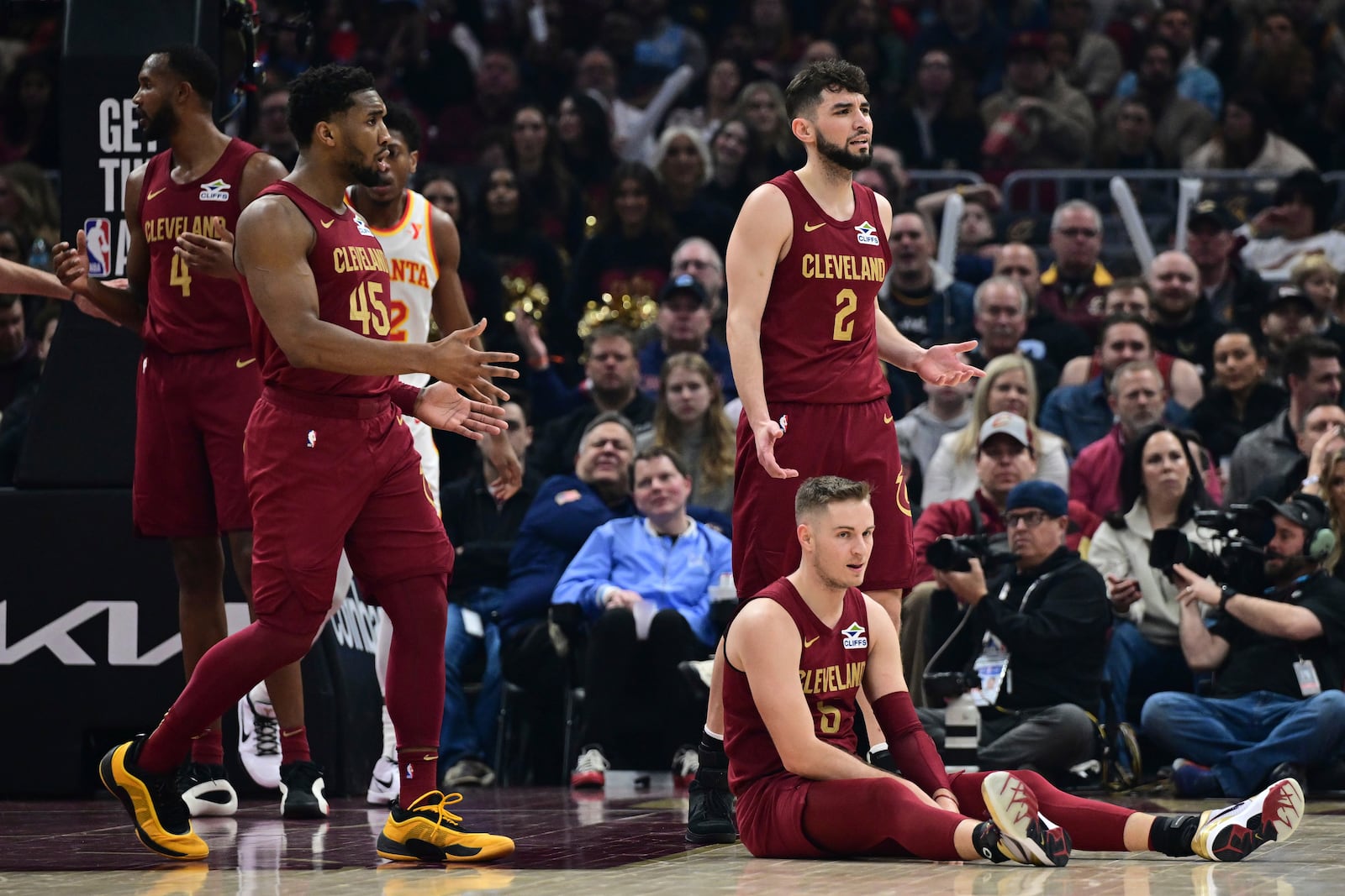 Cleveland Cavaliers guards Sam Merrill, bottom right, Donovan Mitchell (45) and Ty Jerome (2) react after a foul call against Merrill in the first half of an NBA basketball game against the Atlanta Hawks, Thursday, Jan. 30, 2025, in Cleveland. (AP Photo/David Dermer)