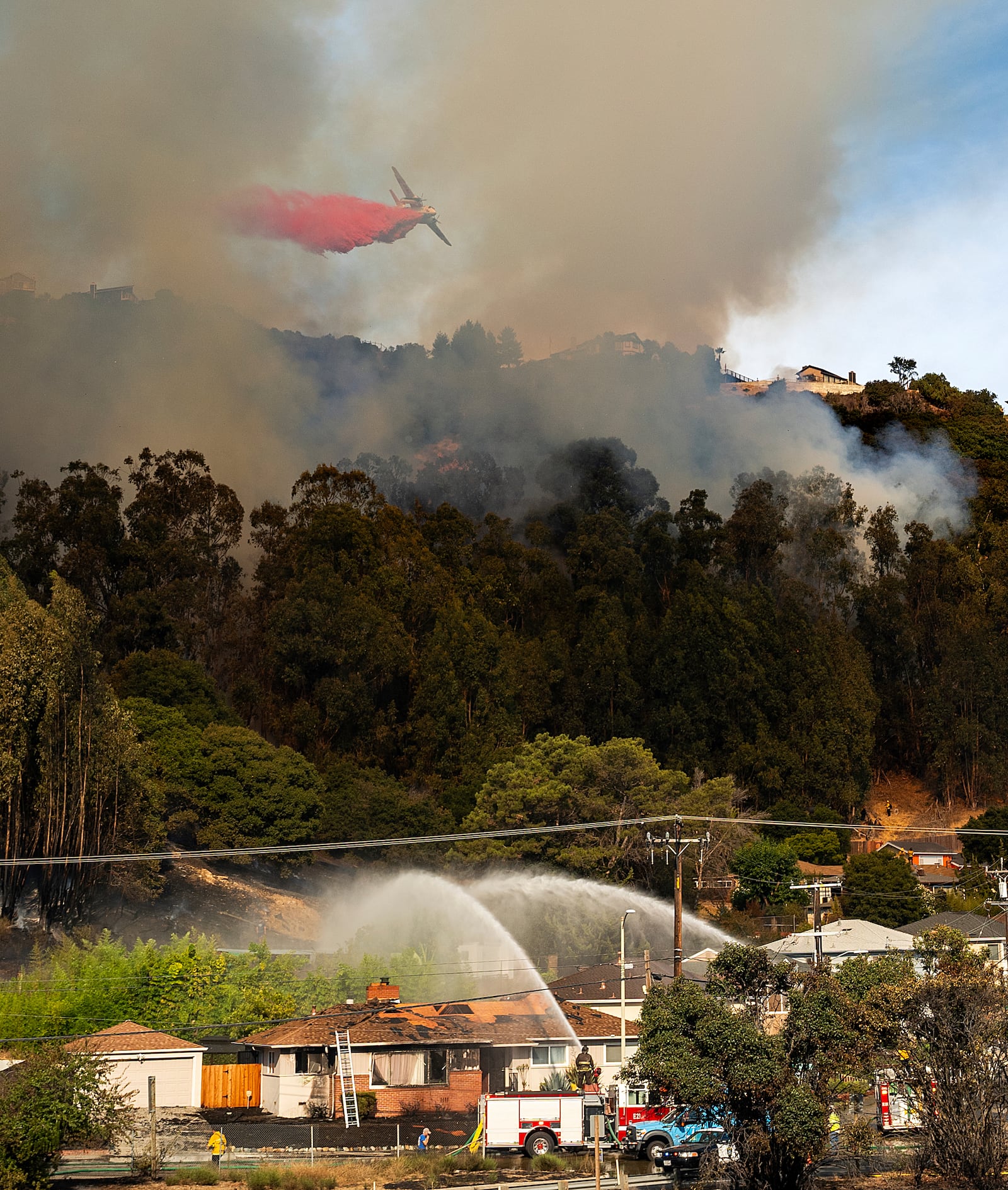 An air tanker drops retardant on a grass fire burning above Interstate 580 in Oakland, Calif., Friday, Oct. 18, 2024. (AP Photo/Noah Berger)