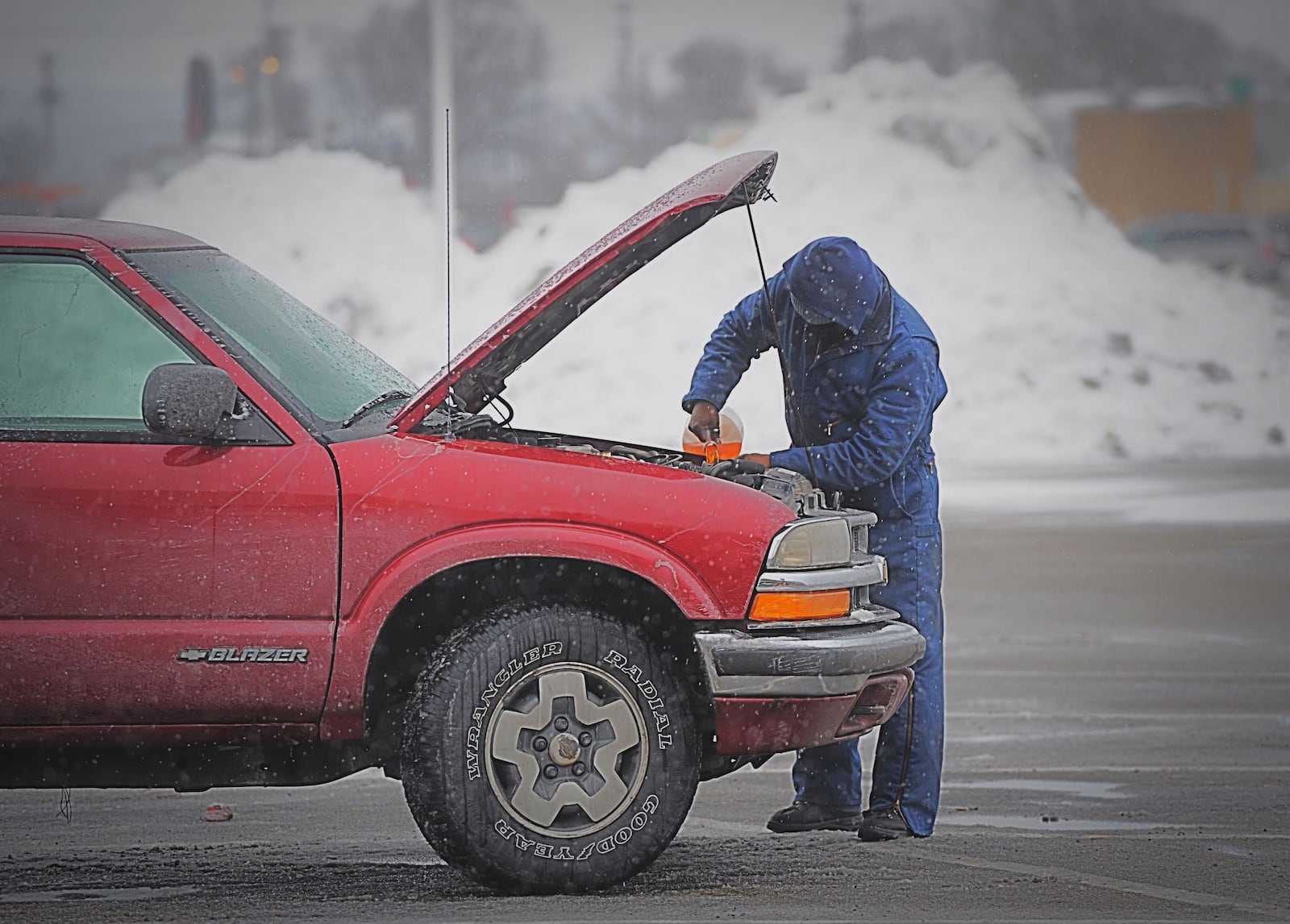 With piles of snow plowed up behind him a man puts windshield washing fluid in his vehicle at the Airway Shopping Center to be prepared for more winter weather Monday, February 15, 2021. MARSHALL GORBY/STAFF