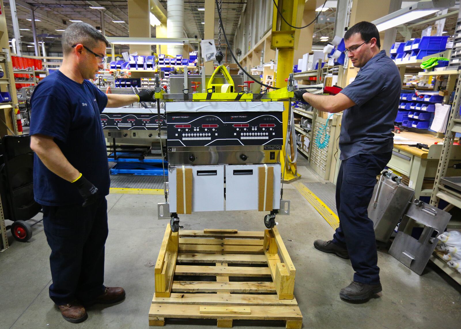 Tony Bowman, left and Christian Kovach move a completed fryer onto a skid for boxing in the plant at the Henny Penny World Headquarters in Eaton.  JIM WITMER / STAFF