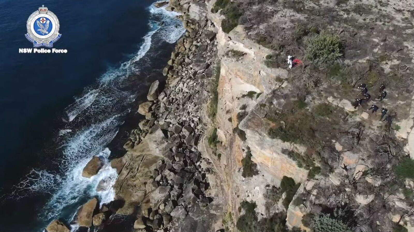 Drone footage from the New South Wales Police shows a search, far right, of a headland in Sydney, Australia, Tuesday, May 12, 2020, following the arrest of a suspect in the cold case killing of American mathematician Scott Johnson. Johnson, 27, was found dead Dec. 10, 1988, at the bottom of the cliff in what authorities believe was a gay hate crime.