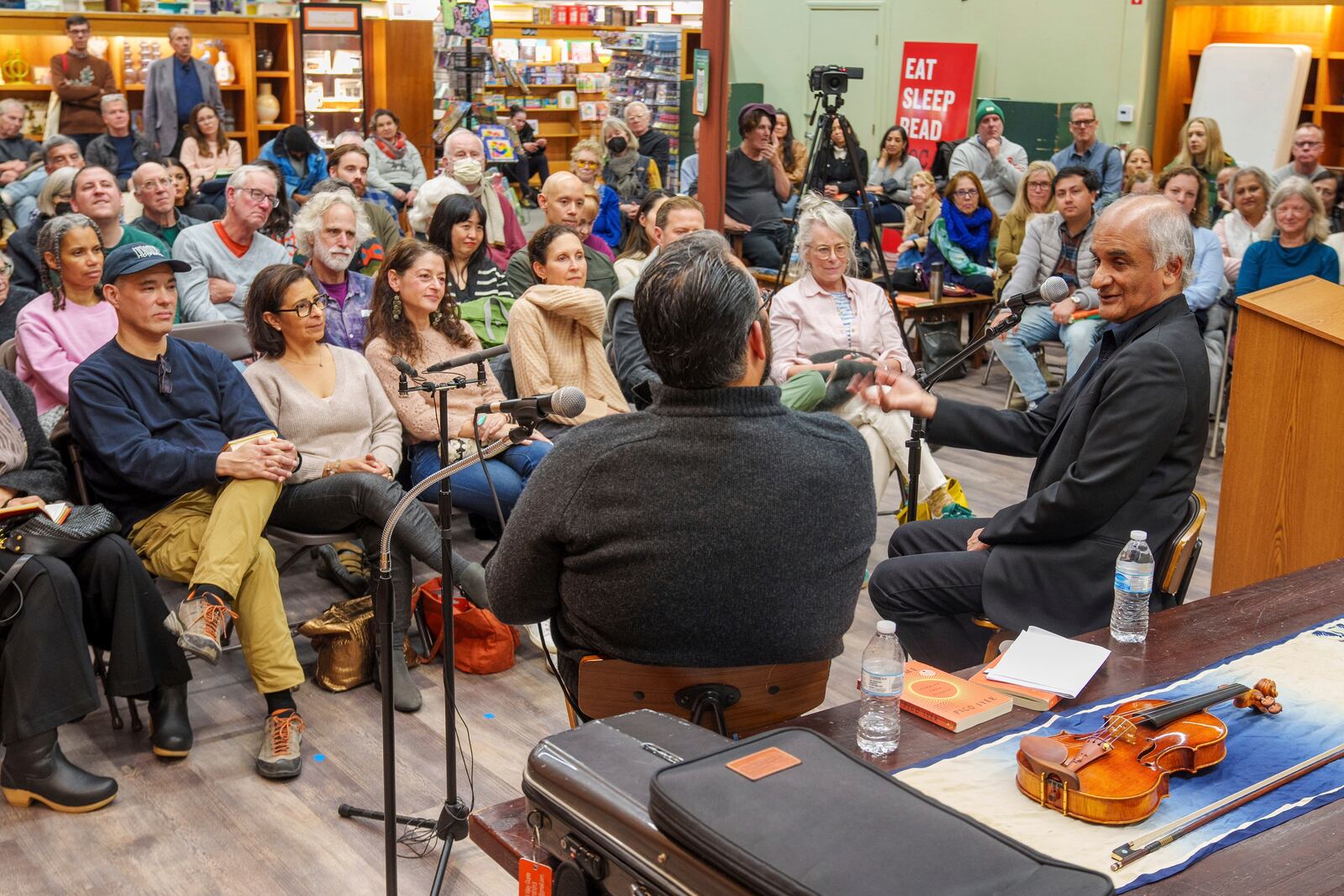 Pico Iyer, the bestselling author of "The Art of Stillness," front right, presents his new book "Aflame: Learning from Silence" in conversation with violinist Vijay Gupta, front left, at Vroman's bookstore in Pasadena, Calif., on Tuesday, Jan. 28, 2025, in the wake of the devastating Eaton Fire that recently swept through parts of Pasadena and Altadena, forcing over 30,000 people to evacuate and burning thousands of structures. (AP Photo/Damian Dovarganes)