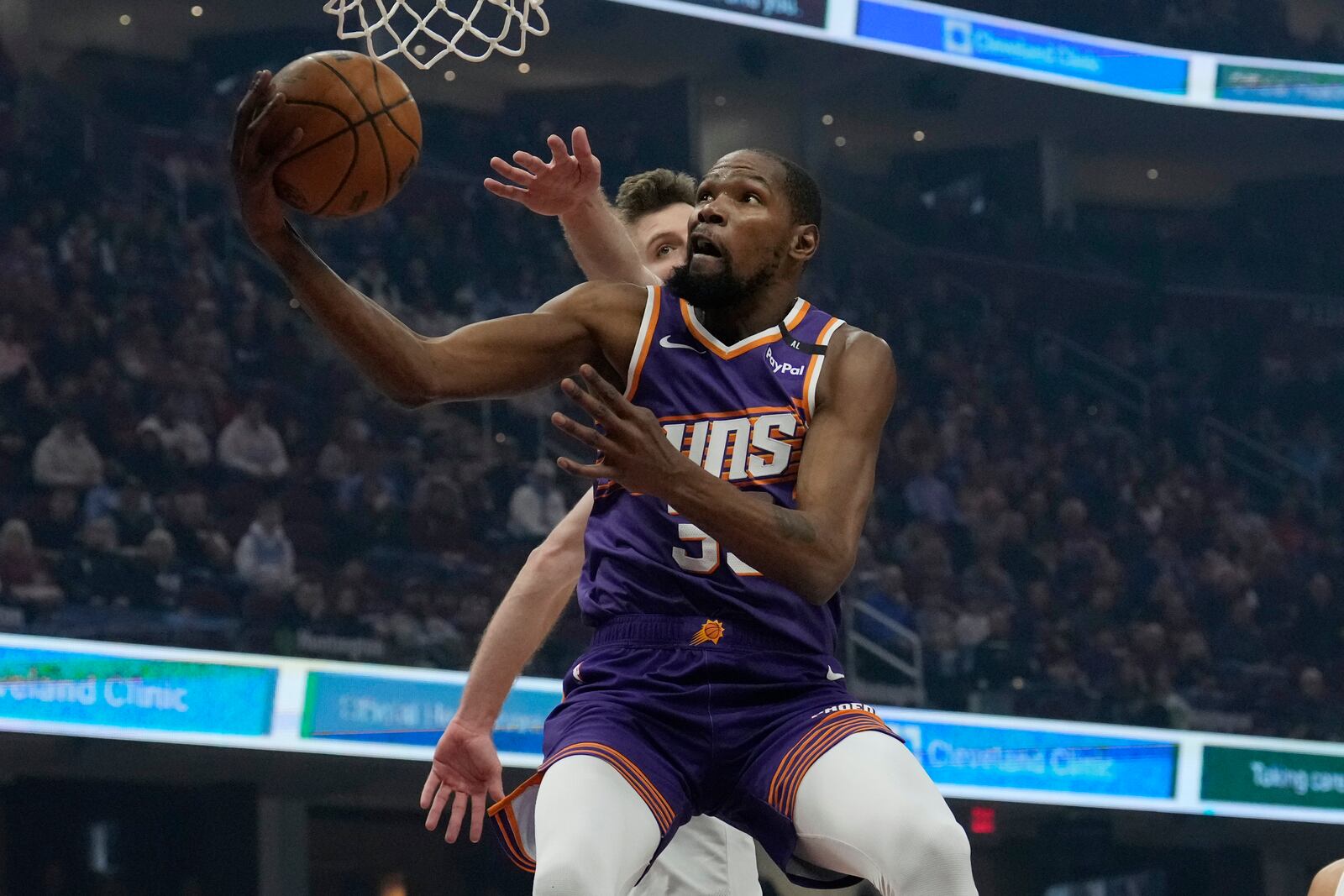 Phoenix Suns forward Kevin Durant, front, goes to the basket past Cleveland Cavaliers forward Dean Wade, back, in the first half of an NBA basketball game, Monday, Jan. 20, 2025, in Cleveland. (AP Photo/Sue Ogrocki)