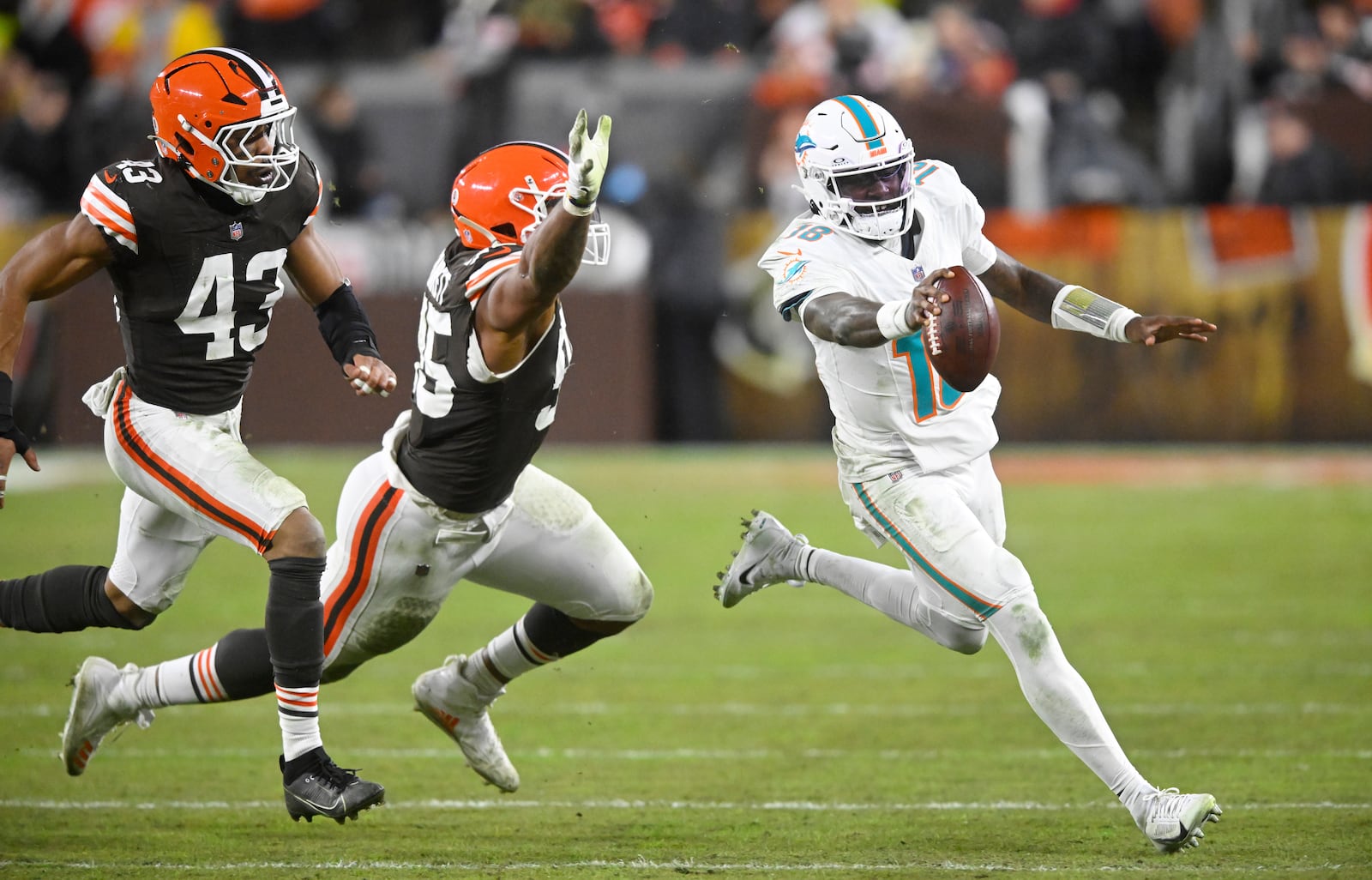 Miami Dolphins quarterback Tyler Huntley, right, scrambles as Cleveland Browns linebacker Mohamoud Diabate (43) and defensive end Myles Garrett (95) defend during the second half of an NFL football game Sunday, Dec. 29, 2024, in Cleveland. (AP Photo/David Richard)