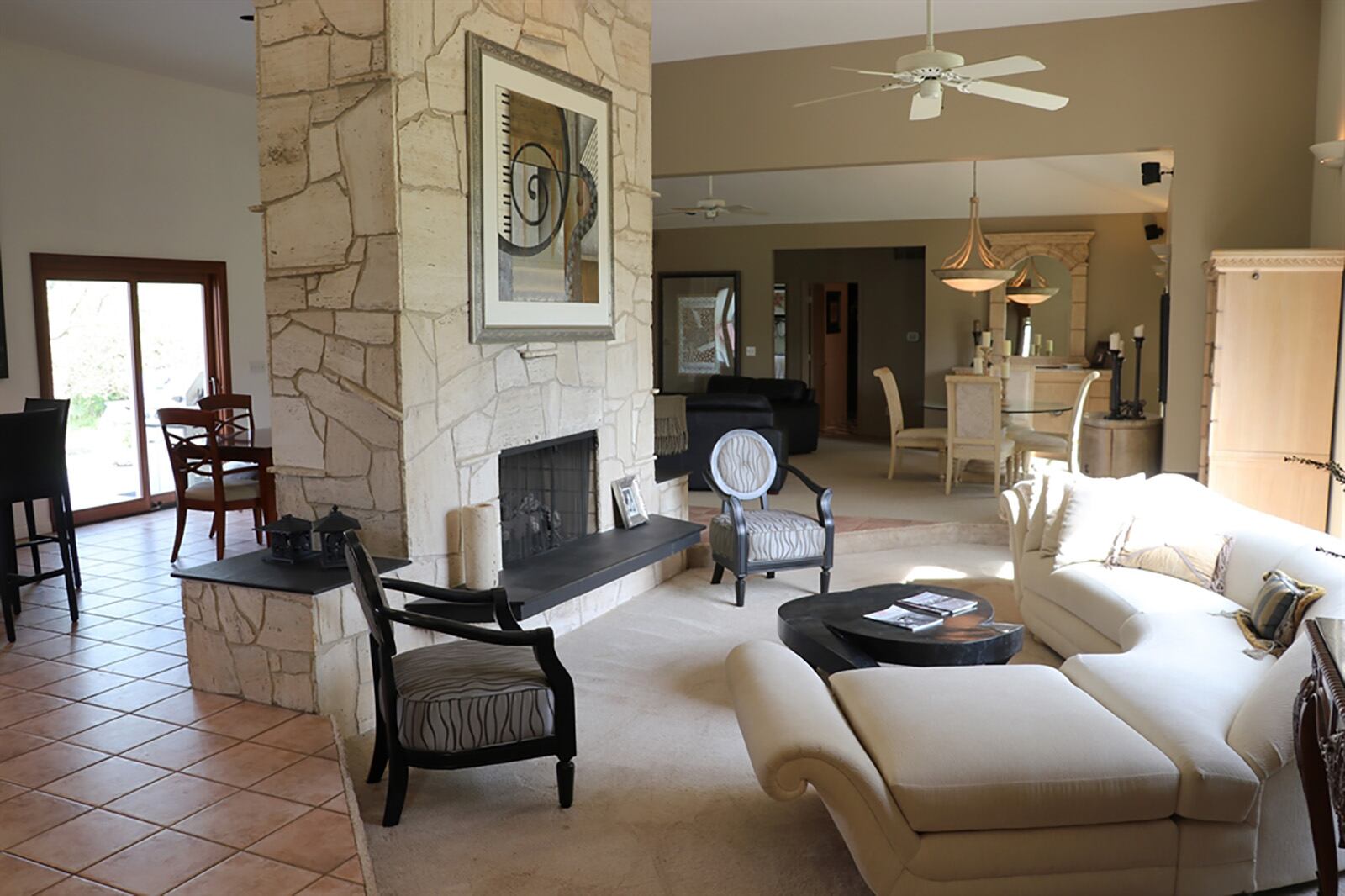 A 2-story, travertine, dual-sided fireplace is the centerpiece to the open floor plan with the more formal design within the sunken living room and a casual design within the breakfast room. CONTRIBUTED PHOTO BY KATHY TYLER