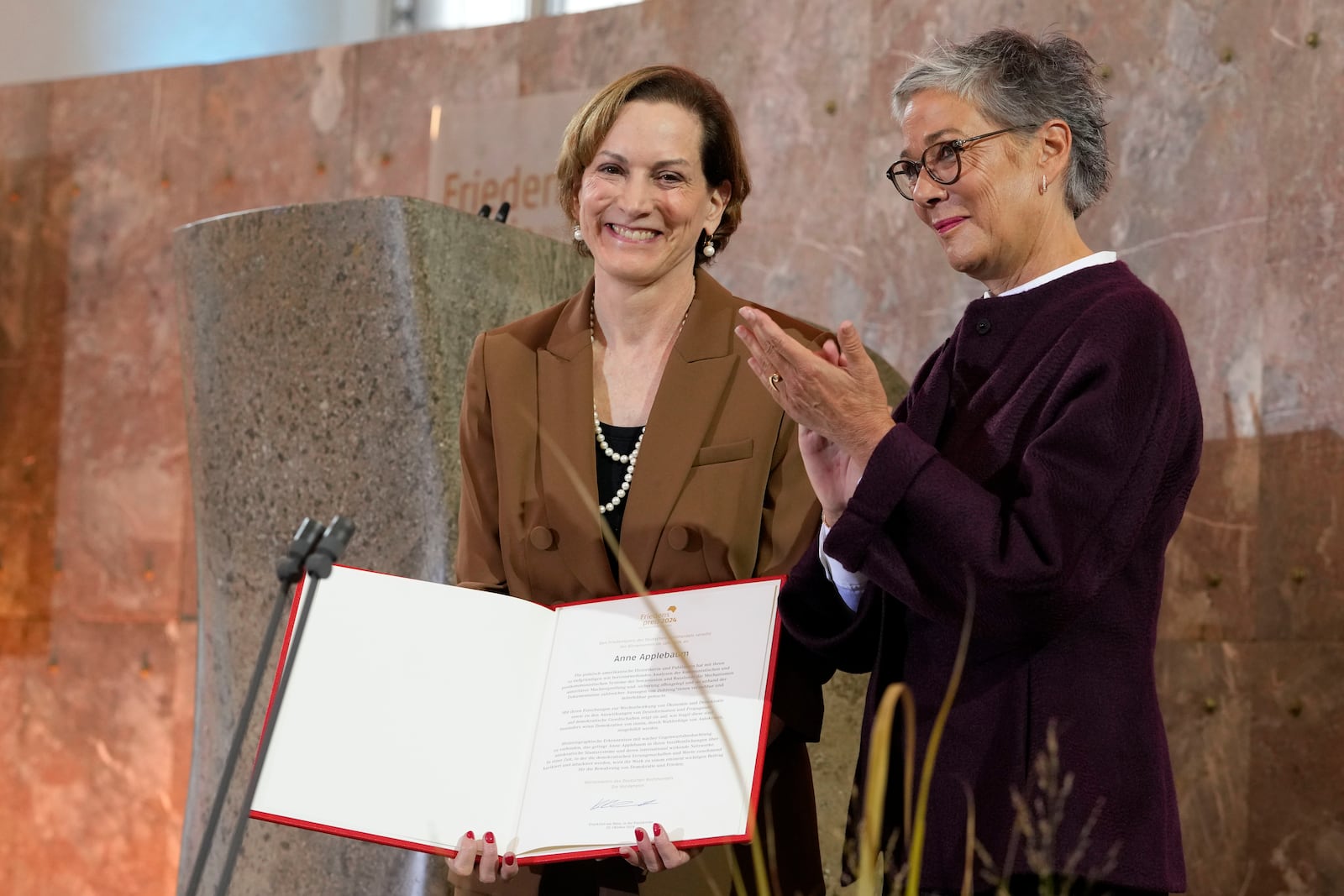 American journalist and historian Anne Applebaum, left, is awarded with the Peace Prize of the German Book Trade by Karin Schmidt-Friderichs, head of the German Publishers and Booksellers Association during a ceremony at the St. Paul's Church in Frankfurt, Germany, Sunday, Oct. 20, 2024.(AP Photo/Martin Meissner, Pool)