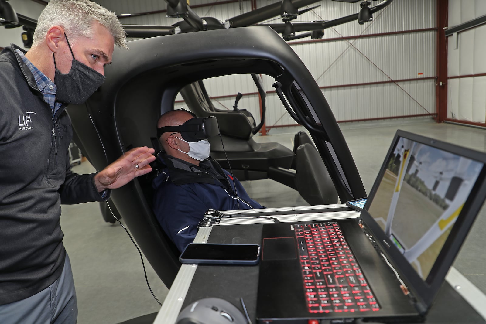 Matthew Chasen, CEO of LIFT Aircraft, instructs a member of the media on how to fly a simulator for LIFT Aircraft’s electric vertical takeoff and landing (eVTOL) vehicle at Springfield-Beckley Municipal Airport Friday. The “flying car” is the first to arrive in Ohio, and is supported by a recent $226,000 grant from JobsOhio’s Ohio Site Inventory Program in infrastructure investments at Springfield-Beckley Municipal Airport. BILL LACKEY/STAFF