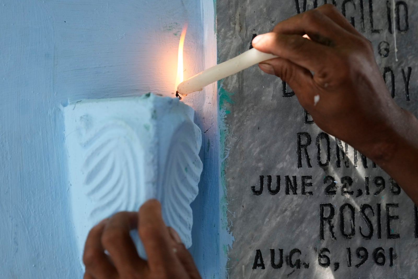 A man lights candles at the tomb of departed loved ones at Manila's North Cemetery, Philippines as the nation observes All Saints Day on Friday, Nov. 1, 2024. (AP Photo/Aaron Favila)