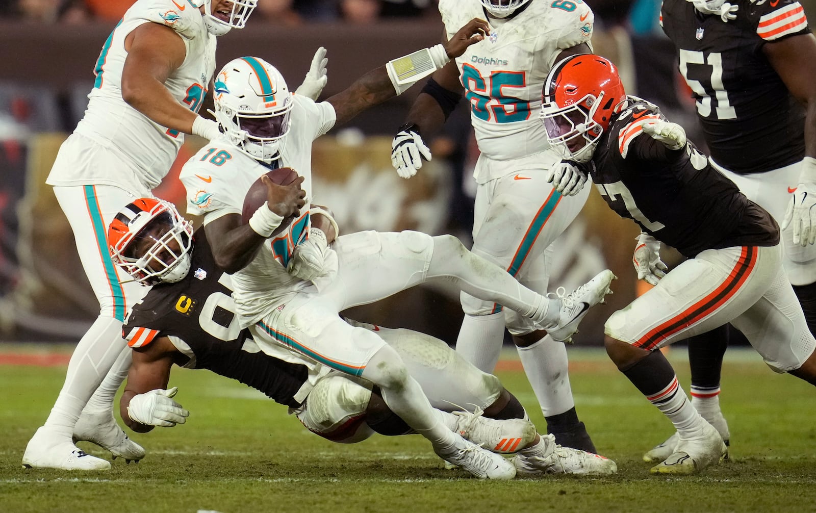 Miami Dolphins quarterback Tyler Huntley (18) is sacked by Cleveland Browns defensive end Myles Garrett, left, during the second half of an NFL football game Sunday, Dec. 29, 2024, in Cleveland. (AP Photo/Sue Ogrocki)