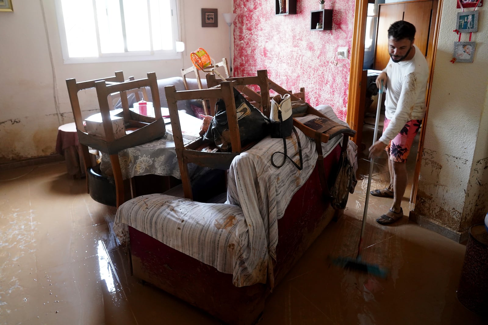 A man cleans his house affected by floods in Valencia, Spain, Wednesday, Oct. 30, 2024. (AP Photo/Alberto Saiz)