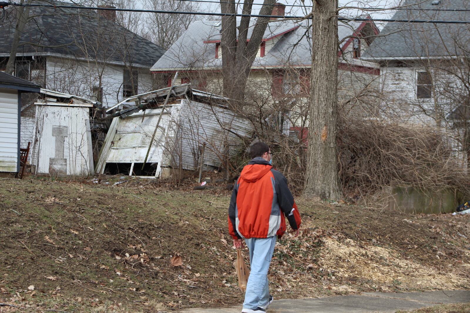 A pedestrian walks by vacant and deteriorating properties in north Dayton. CORNELIUS FROLIK / STAFF