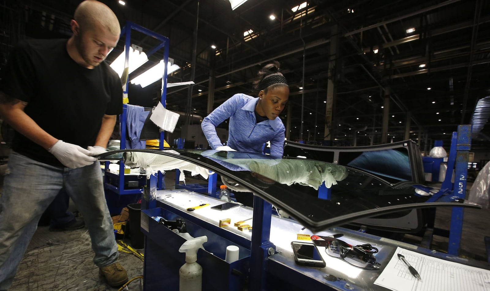 Fuyao Glass America has progressed at a pace that is years ahead of its original schedule and now employs more than 2,000 people. Dustin Sparkman, left, and Deraesha Stewart work as a team to clean and quality check windshields in the Moraine plant..  TY GREENLEES / STAFF