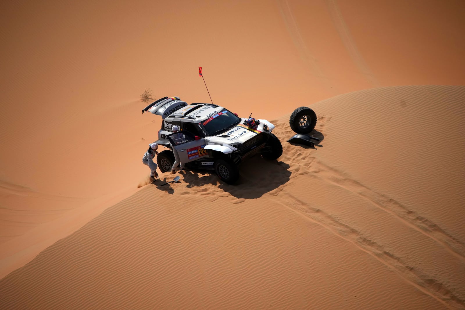 Driver Guillaume De Mevius and co-driver Mathieu Baumel repair a wheel during the tenth stage of the Dakar Rally between Haradh and Shubaytah, Saudi Arabia, Wednesday, Jan. 15, 2025. (AP Photo/Christophe Ena)