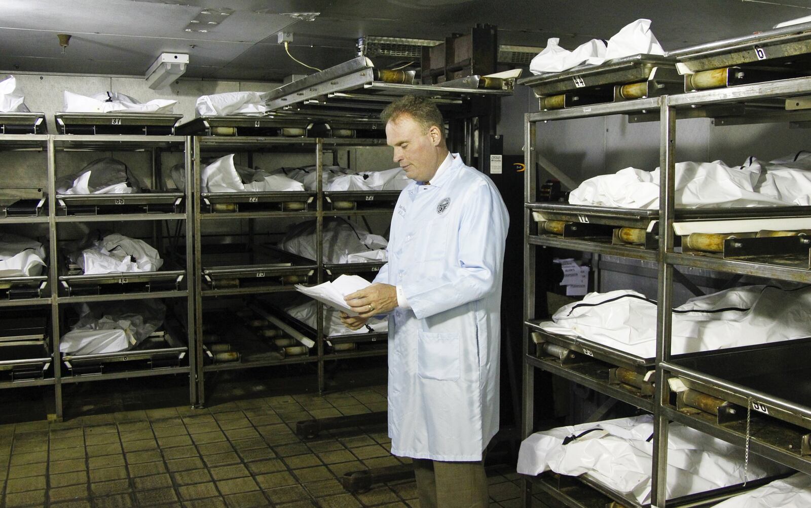 Montgomery County Coroner Dr. Kent Harshbarger is seen in the cooler at the morgue where up to 60 percent of the bodies are those who died of drug overdoses. CHRIS STEWART / STAFF