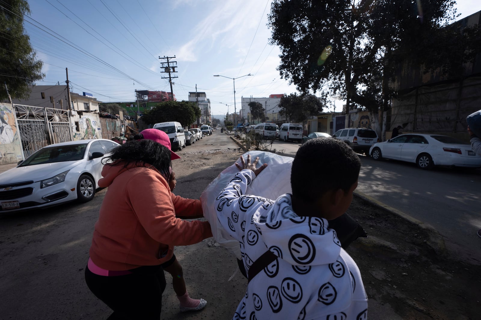 Margelis Rodriguez, left, of Venezuela, pushes a stroller packed with laundry as her son Mickel steadies the load on their way to a nearby laundromat in Tijuana, Mexico, Friday, Jan. 31, 2025. (AP Photo/Gregory Bull)