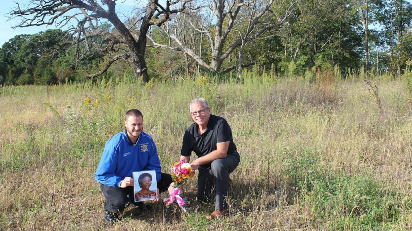 Grundy County, Ill., Coroner John Callahan, right, and his chief deputy coroner, Brandon Johnson, leave flowers and an artist's rendering Oct. 1, 2019, of homicide victim Jane Seneca Doe near the site where her body was found Oct. 2, 1976.