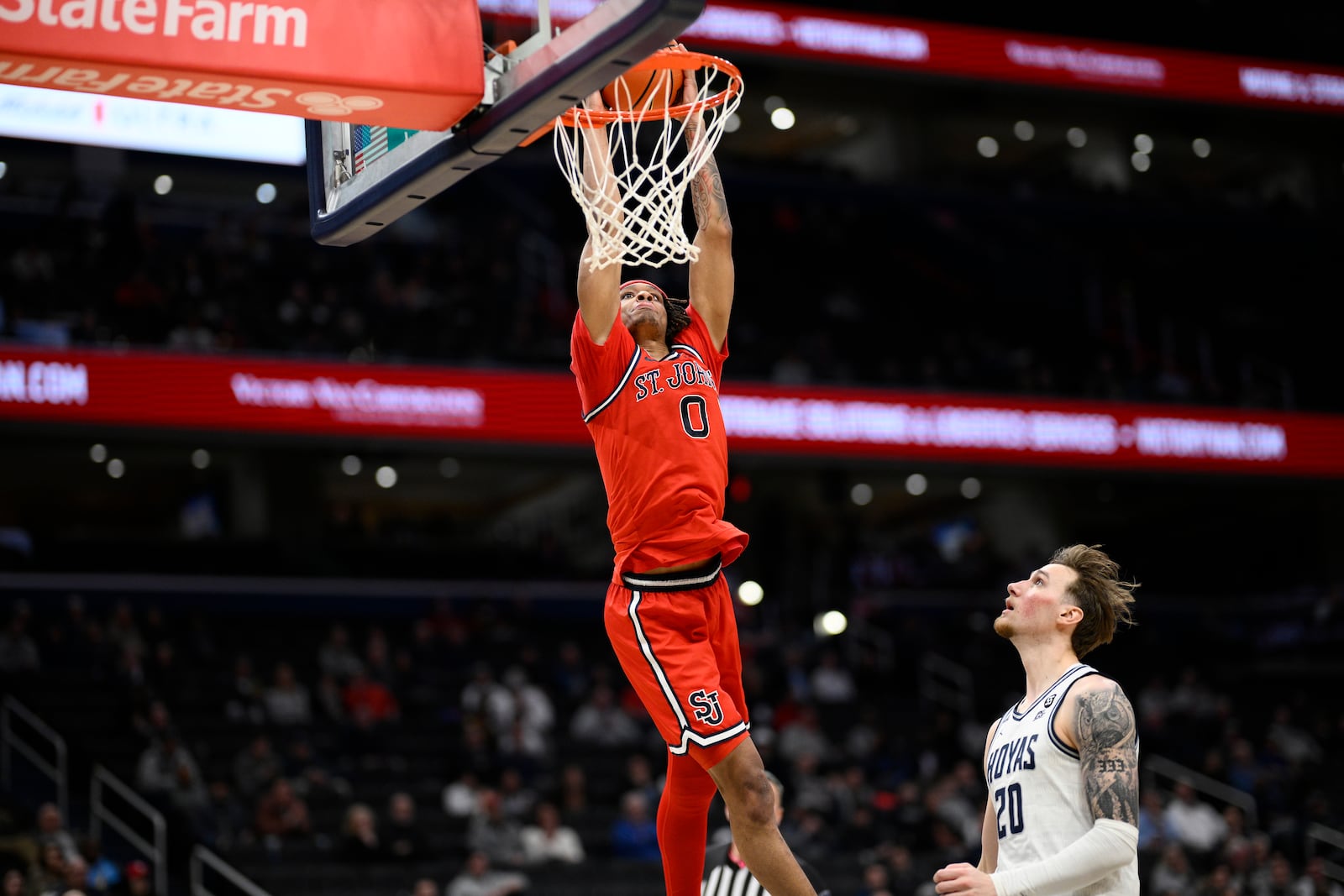 St. John's guard Aaron Scott (0) goes to the basket past Georgetown forward Drew Fielder (20) during the second half of an NCAA college basketball game, Tuesday, Jan. 28, 2025, in Washington. (AP Photo/Nick Wass)