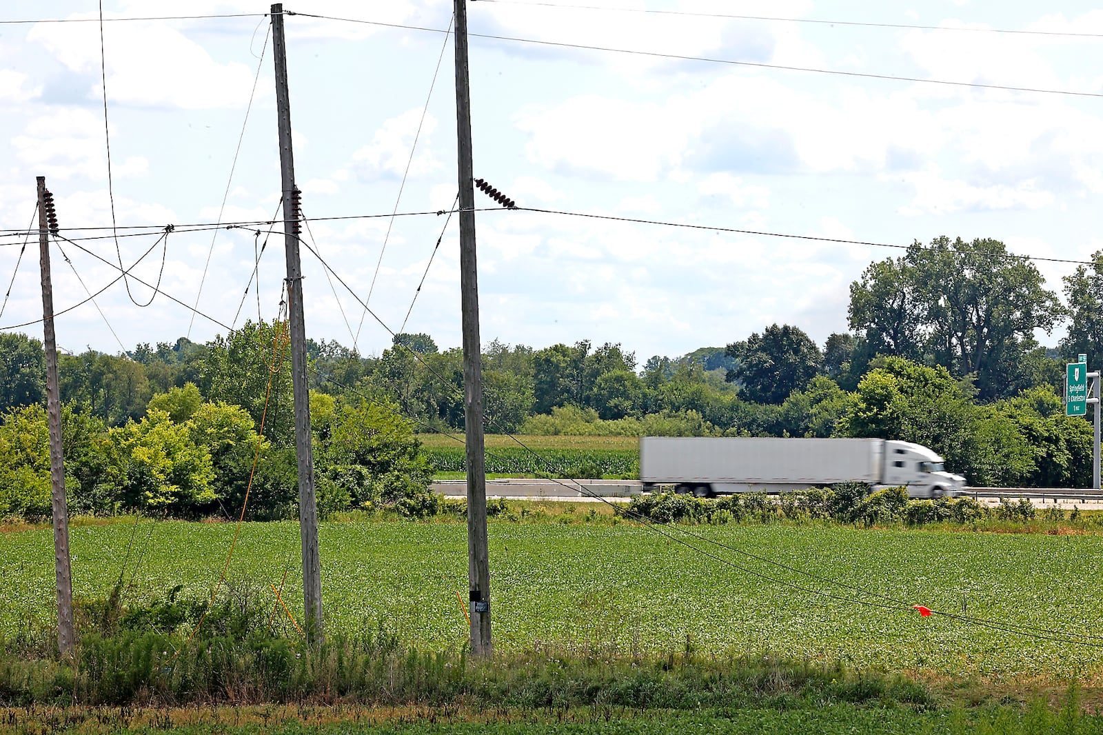 Traffic speeds by on Interstate 70 Monday, July 31, 2023. The interstate was closed for several hours Saturday after a helicopter accidentally cut the power lines, pictured in the foreground, that stretch over the roadway. The helicopter then crashed, and the pilot was pronounced dead. BILL LACKEY/STAFF