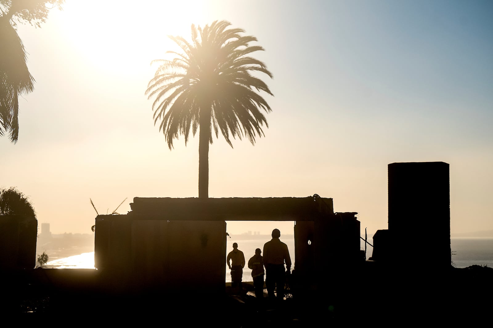 Firefighters from an Oregon strike team survey damage at a Sunset Blvd. home leveled by the Palisades Fire in the Pacific Palisades community of Los Angeles on Sunday, Jan. 12, 2025. (AP Photo/Noah Berger)